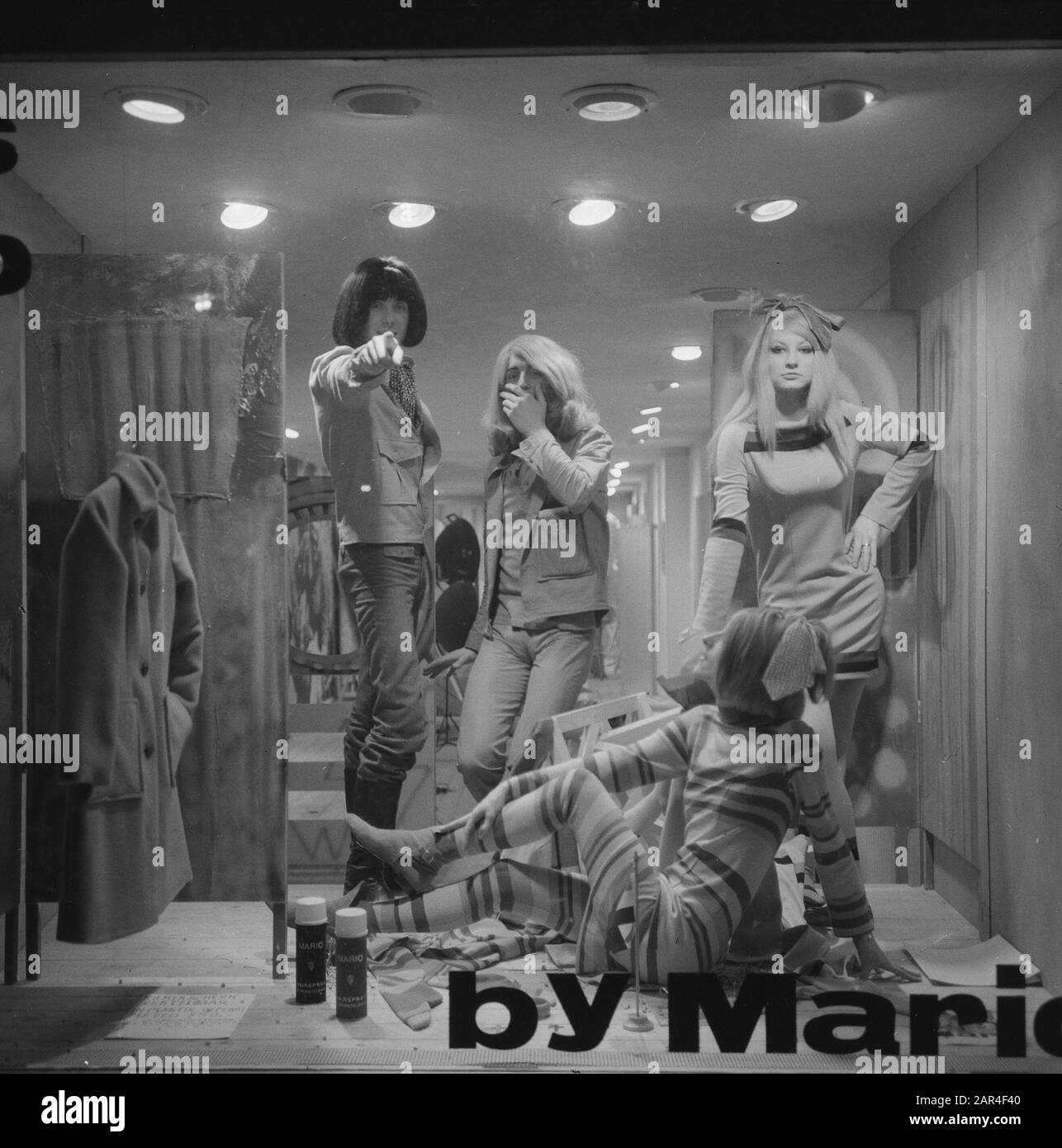 Parrucchiere Mario, titolare del parrucchiere The Trend di Amsterdam, con parrucca Mario e pittore Simon Postuma (con parrucche) mentre si posa in vetrina, insieme a due modelli Data: 5 novembre 1965 luogo: Amsterdam, Noord-Holland Parole Chiave: Modelli fotografici, parrucchieri, pittori, moda, parrucche Nome personale: Postuma, Simon Foto Stock