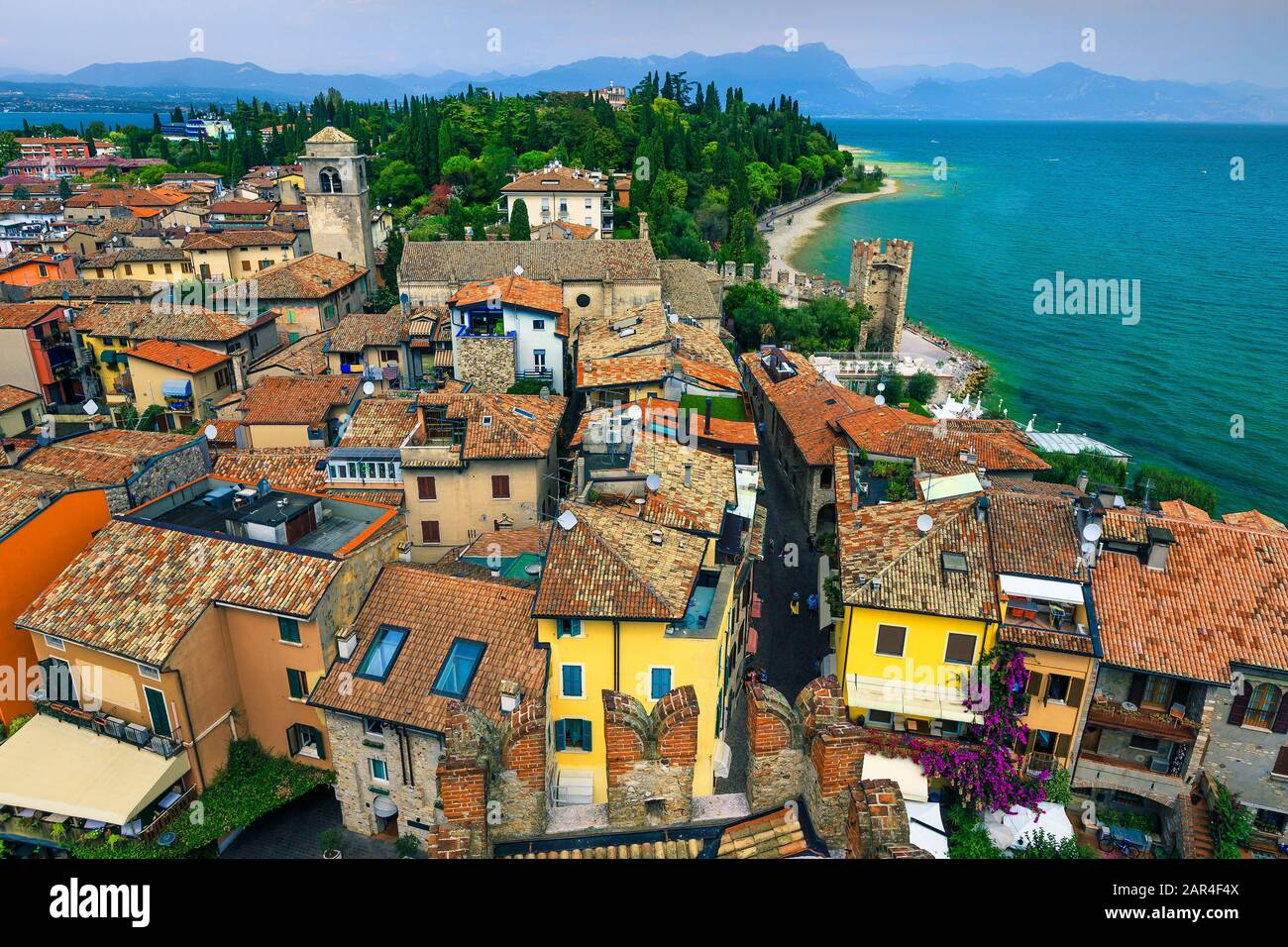 Splendida vista sui tetti antichi e sulle strade turistiche della località di Sirmione dal castello Scaliger. Bellissimo lago di Garda con montagne sullo sfondo, L Foto Stock