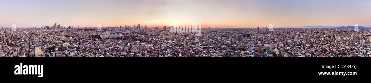 Il sole che sorge sopra La CittA' Piu' Grande di Tokyo in un panorama aereo sopra le cime del tetto e le torri dei grattacieli. Shinjuku, Shibuya e cono bianco del Monte Fuji su un di Foto Stock