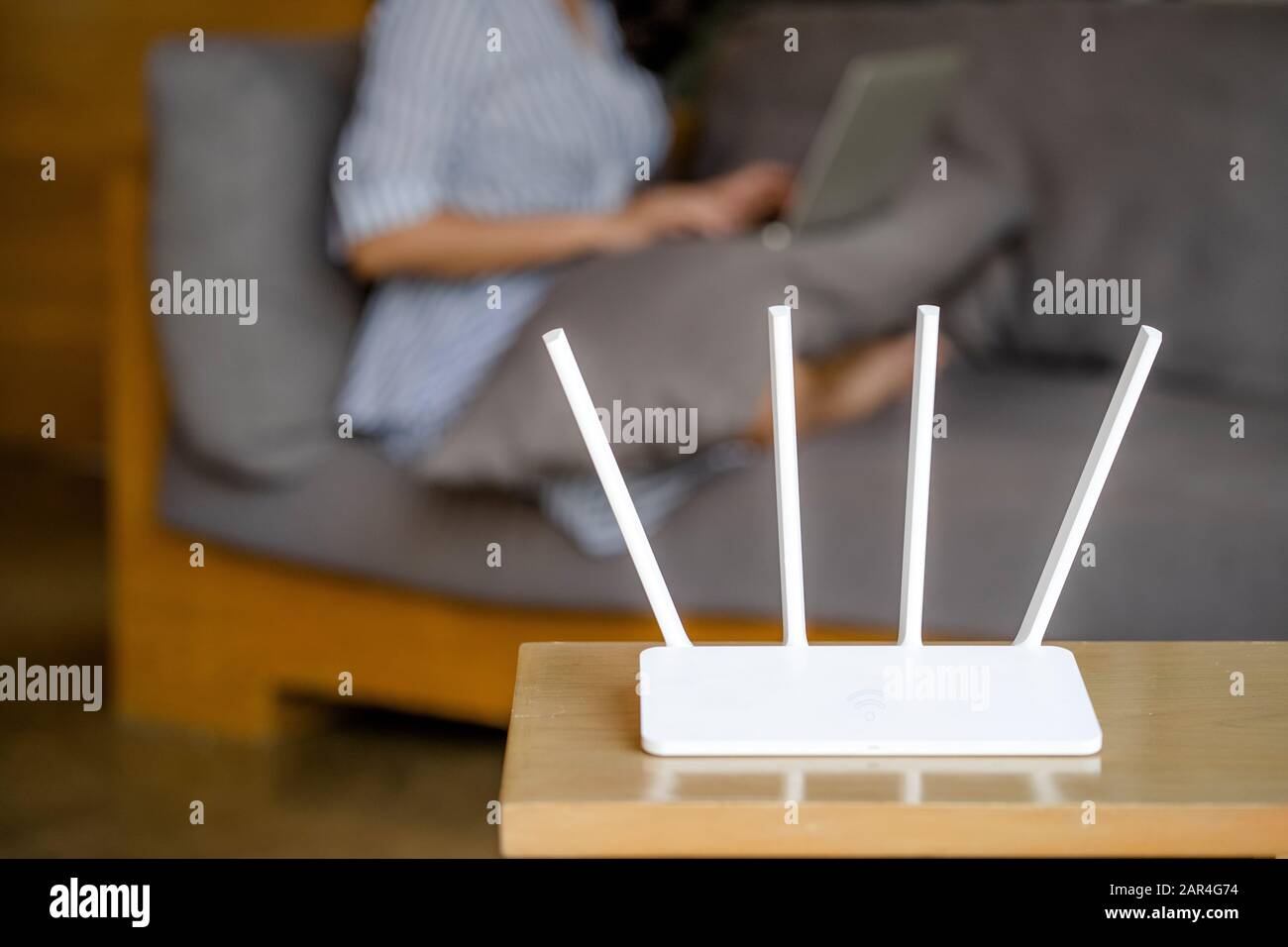 Router wireless e donna che utilizzano un computer portatile in ufficio. Router wireless a banda larga home laptop computer telefono wifi concetto Foto Stock