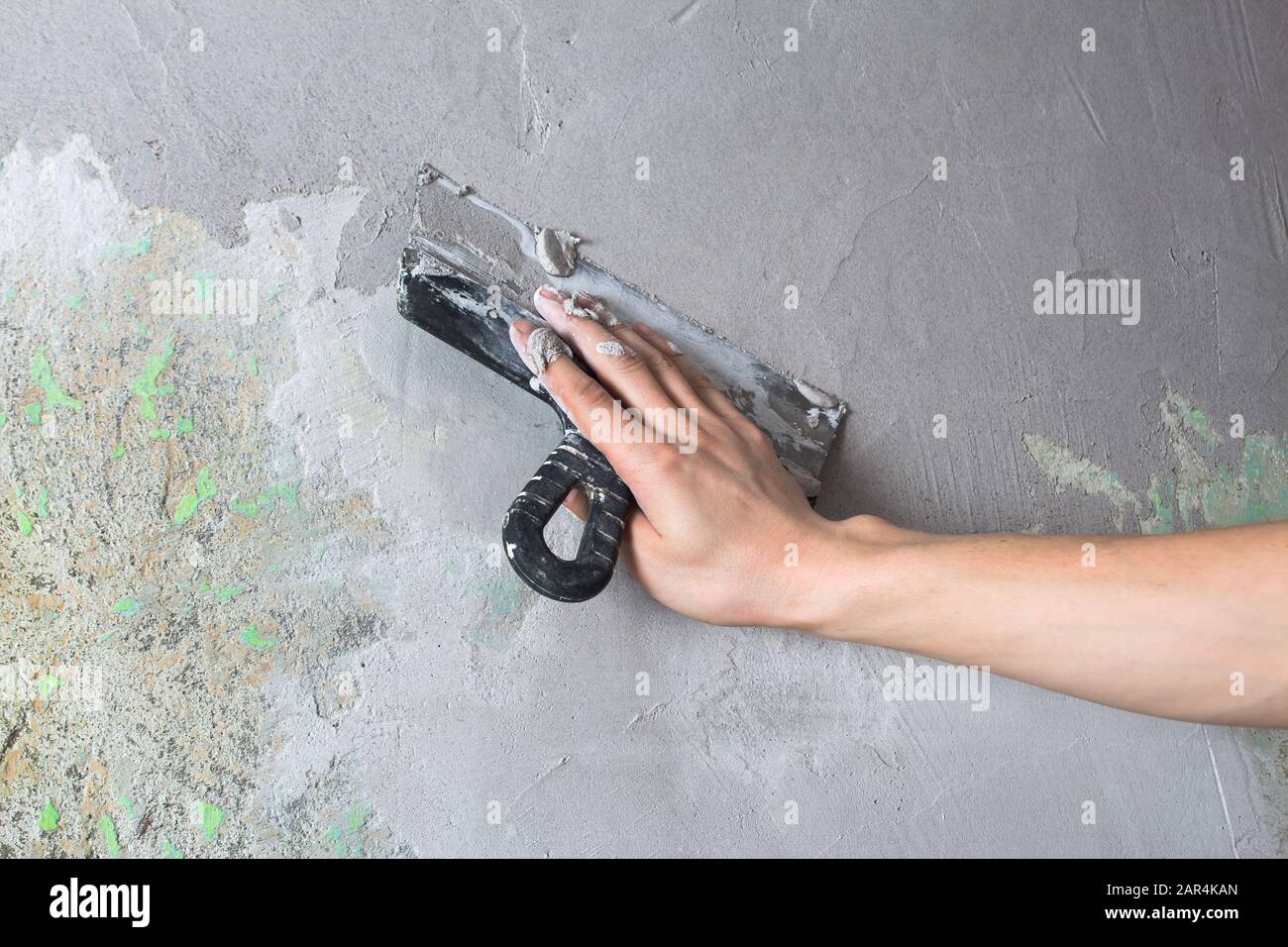 Riparare il muro. Intonacate il muro con una spatola. Lavori interni di costruzione e finitura. Il costruttore mette intonaco sulla parete. Mano che tiene uno spat Foto Stock