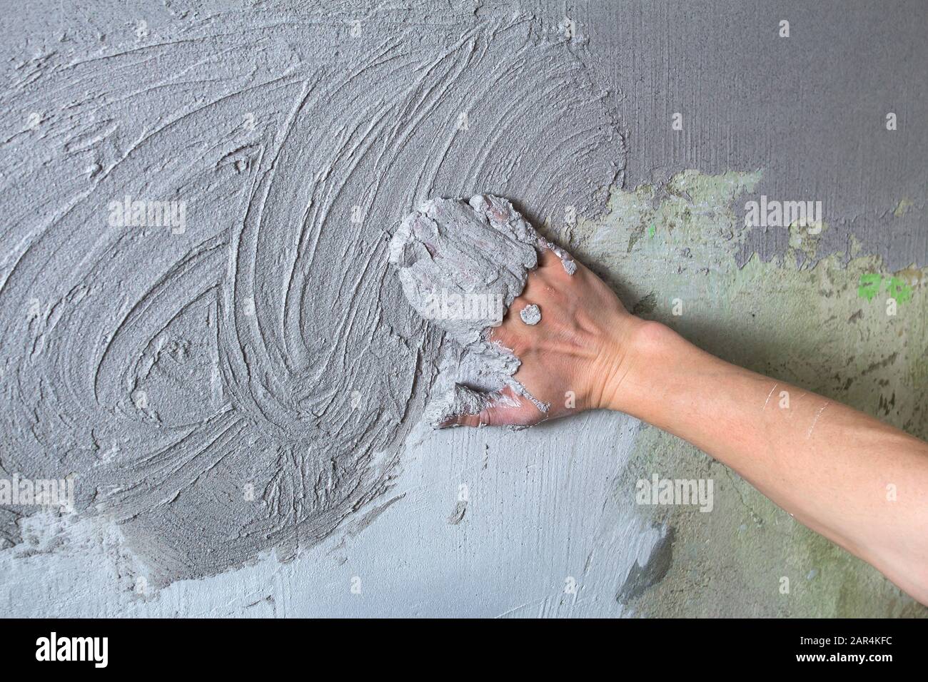 Il costruttore di intonaci mette il gesso sulla parete con la mano. Costruzione interna e lavori di finitura. La mano tiene il mix di costruzione e mq Foto Stock