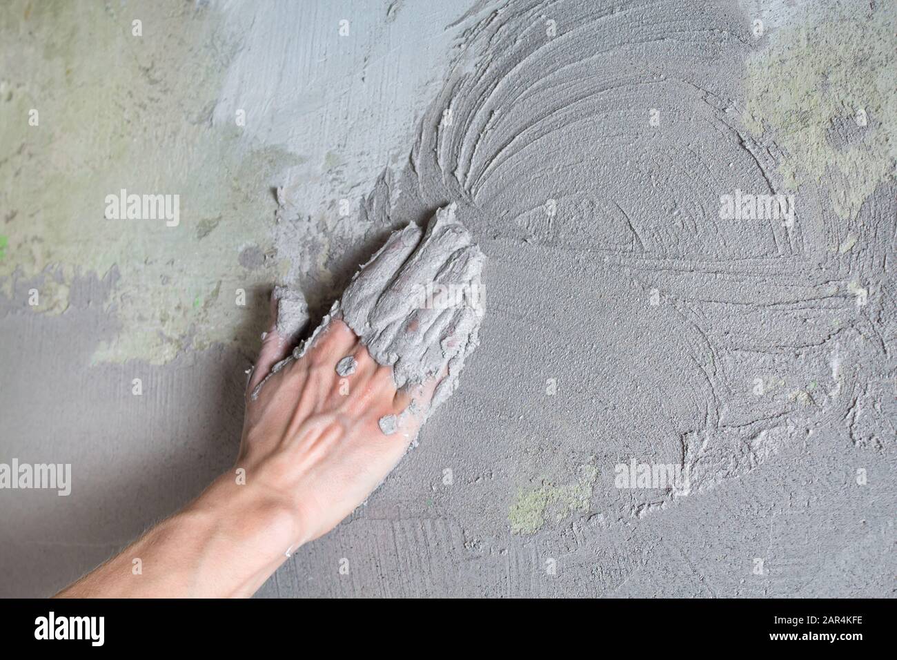 Il costruttore di intonaci mette il gesso sulla parete con la mano. Costruzione interna e lavori di finitura. La mano tiene il mix di costruzione e mq Foto Stock