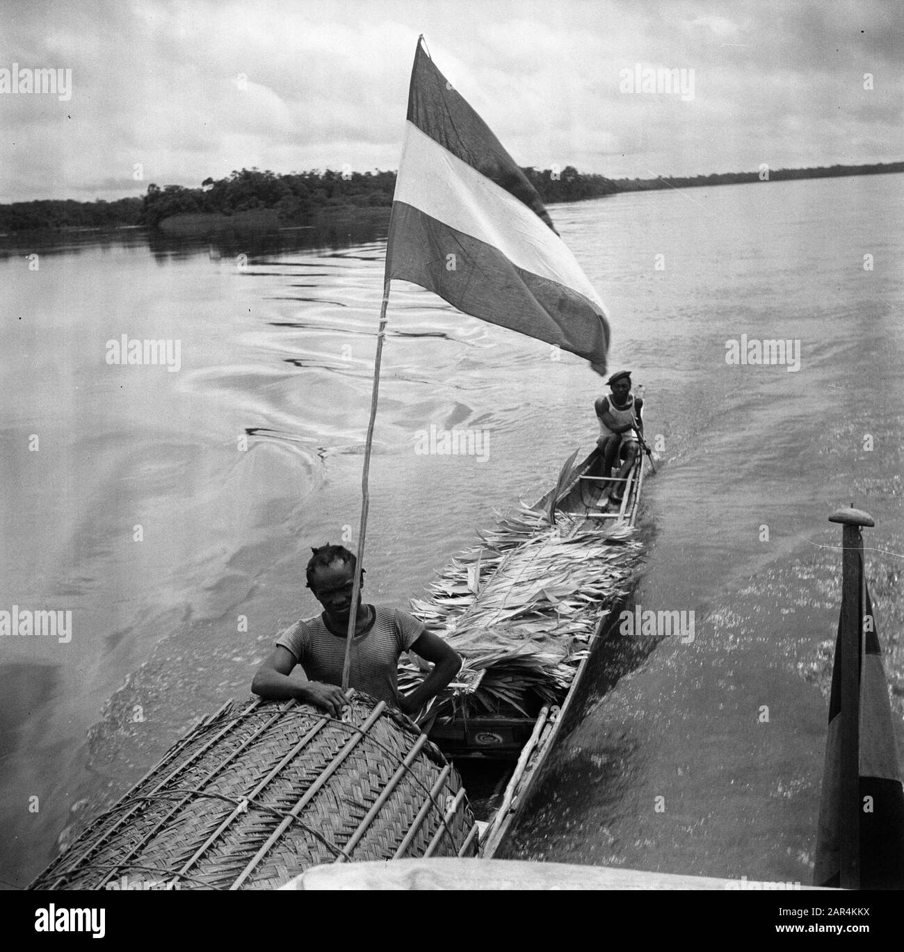 Viaggio nel Suriname e nelle Antille Olandesi un corallo con foglie di palma sul Marowijnerivier. La korjaal porta una bandiera olandese Data: 1947 posizione: Marowijne, Suriname Parole Chiave: Popolazione indigena, palme, fiumi, navi, bandiere Foto Stock