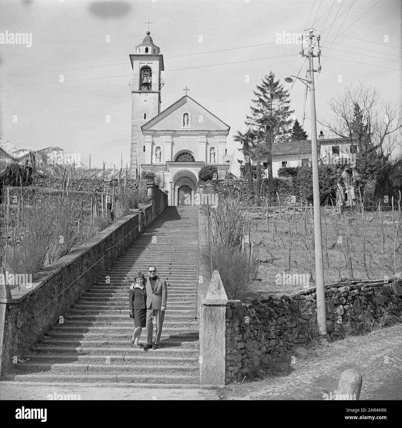 Vivere ad Ascona un uomo e una donna su una scala di fronte ad una chiesa all'estero. Ascona, Svizzera? Date: 1960 Location: Italy Keywords: Signore, esterno, chiese, scale Foto Stock
