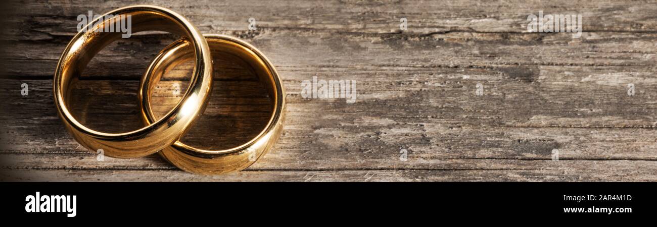 Due golden gli anelli di nozze su sfondo di legno con copia spazio per il testo Foto Stock