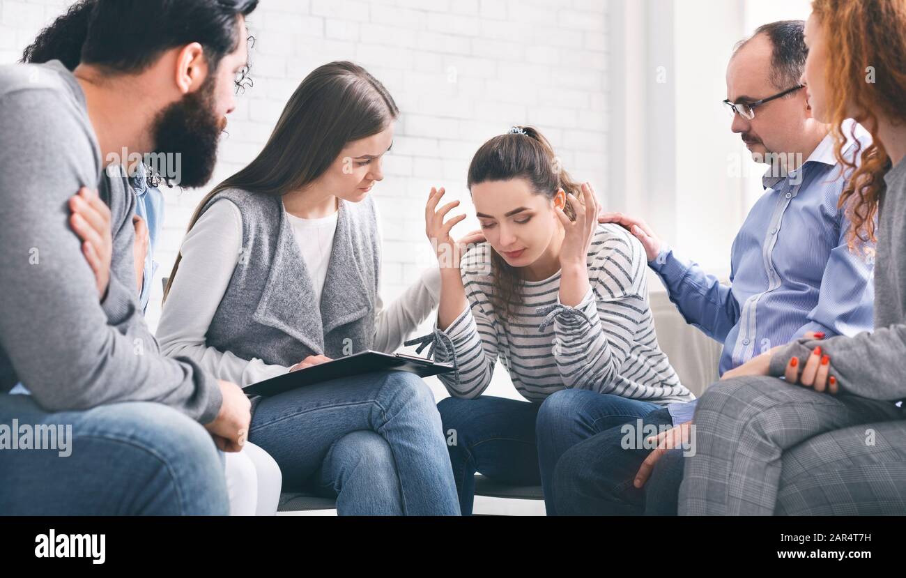 Donna depressa che condivide i suoi problemi con il gruppo sulla sessione di terapia Foto Stock