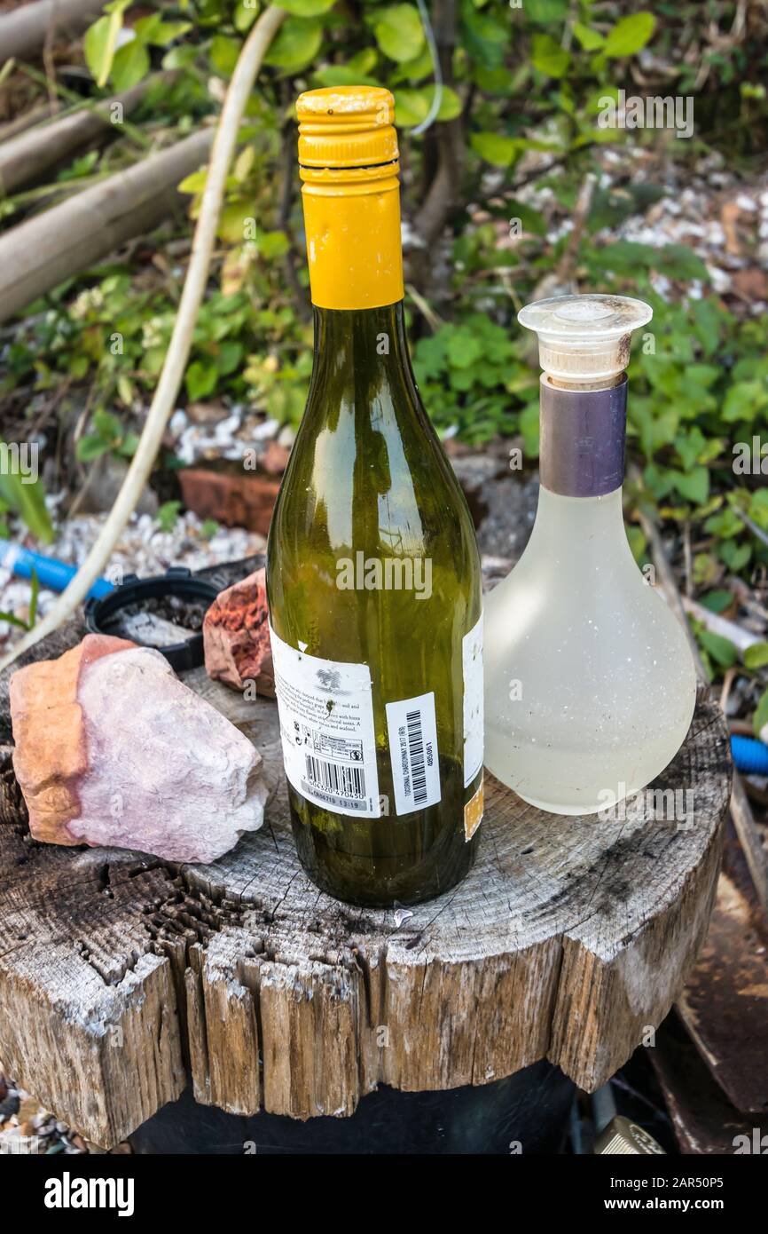 Bottiglie semi-piene su un moncone all'aperto Foto Stock