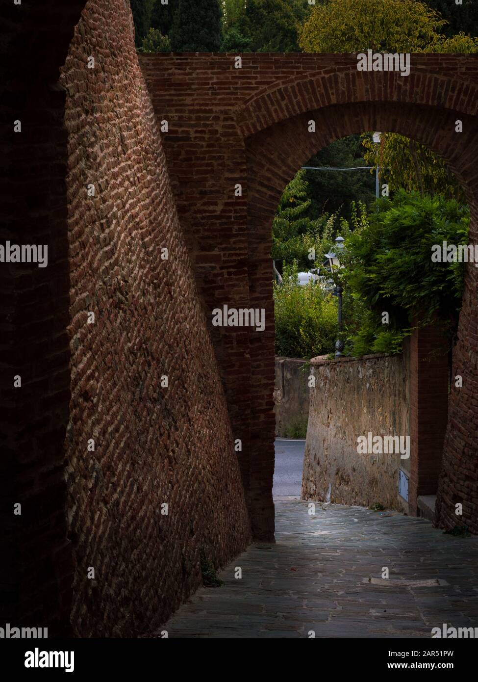 Uno stretto passaggio tra due pareti di mattoni rossi in una vecchia città medievale italiana con una splendida vista Foto Stock