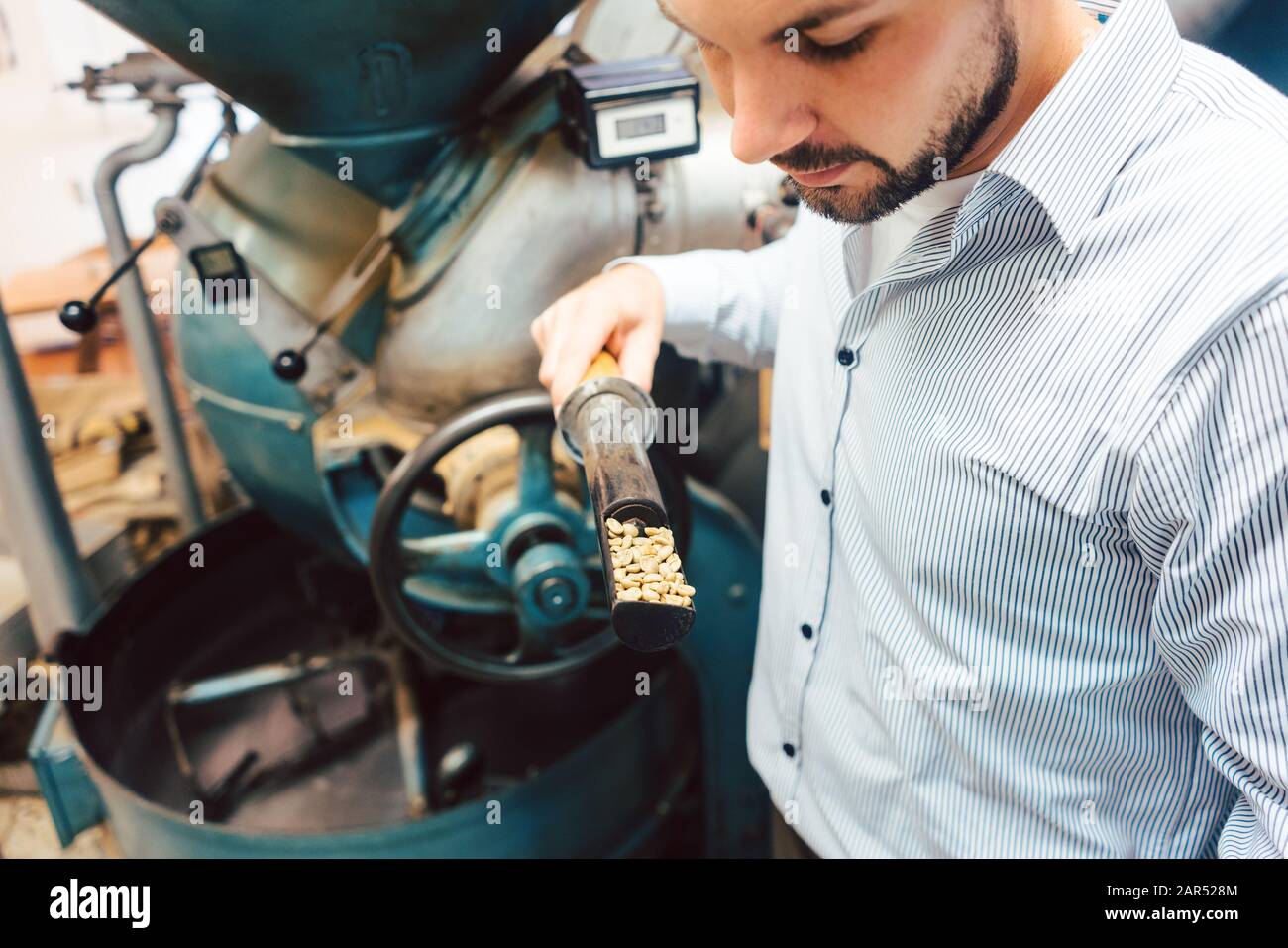 Barista che torreda il caffè con una macchina Foto Stock