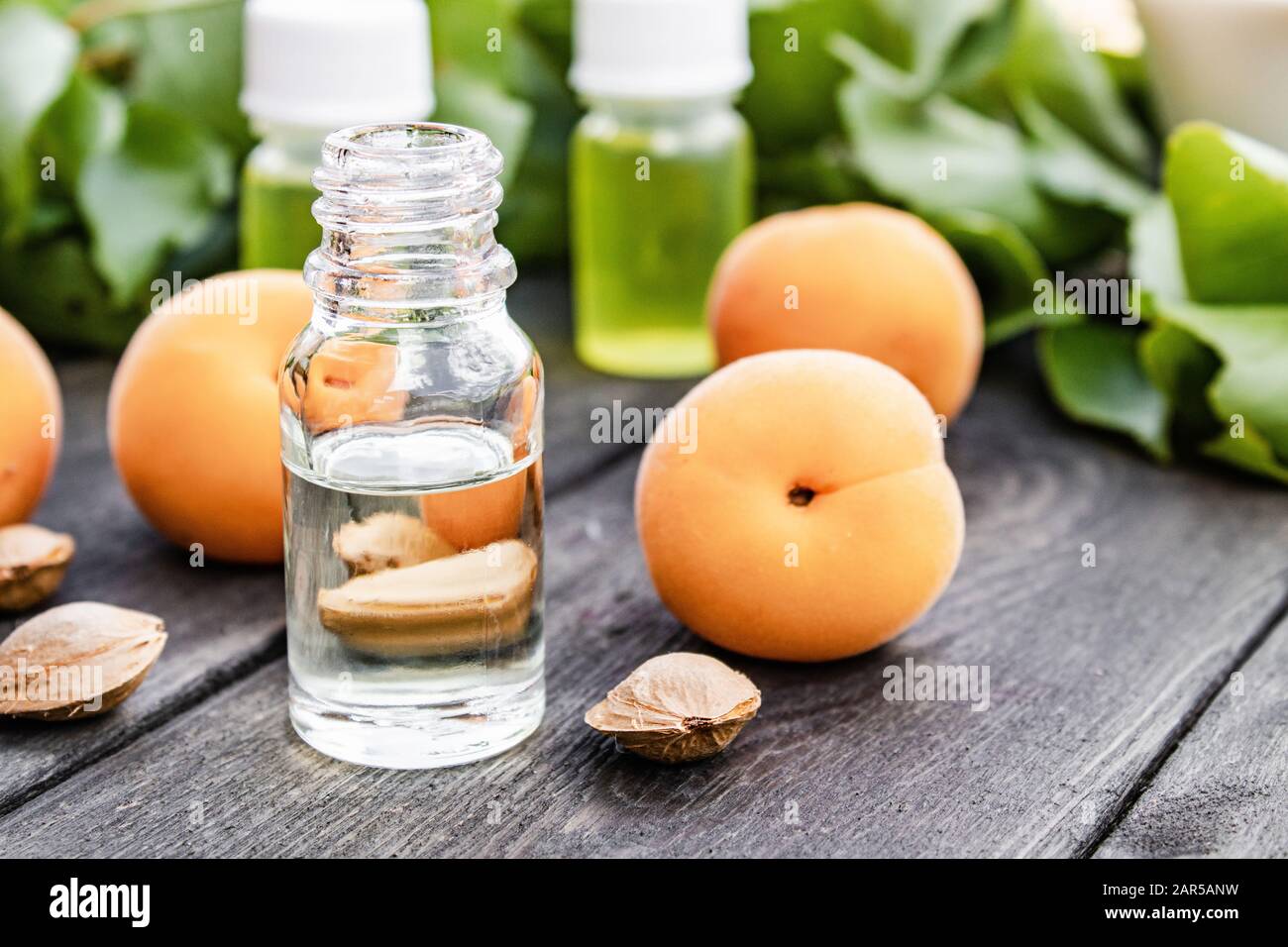 Olio di albicocca in vaso di vetro da vicino a un tavolo vicino a un albicocca gialla matura. Messa a fuoco selettiva. Foto Stock