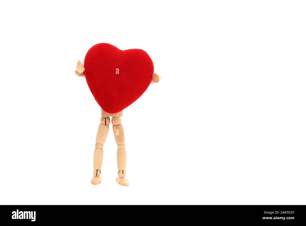 Una bambola di legno che tiene un cuore su uno sfondo bianco Foto Stock