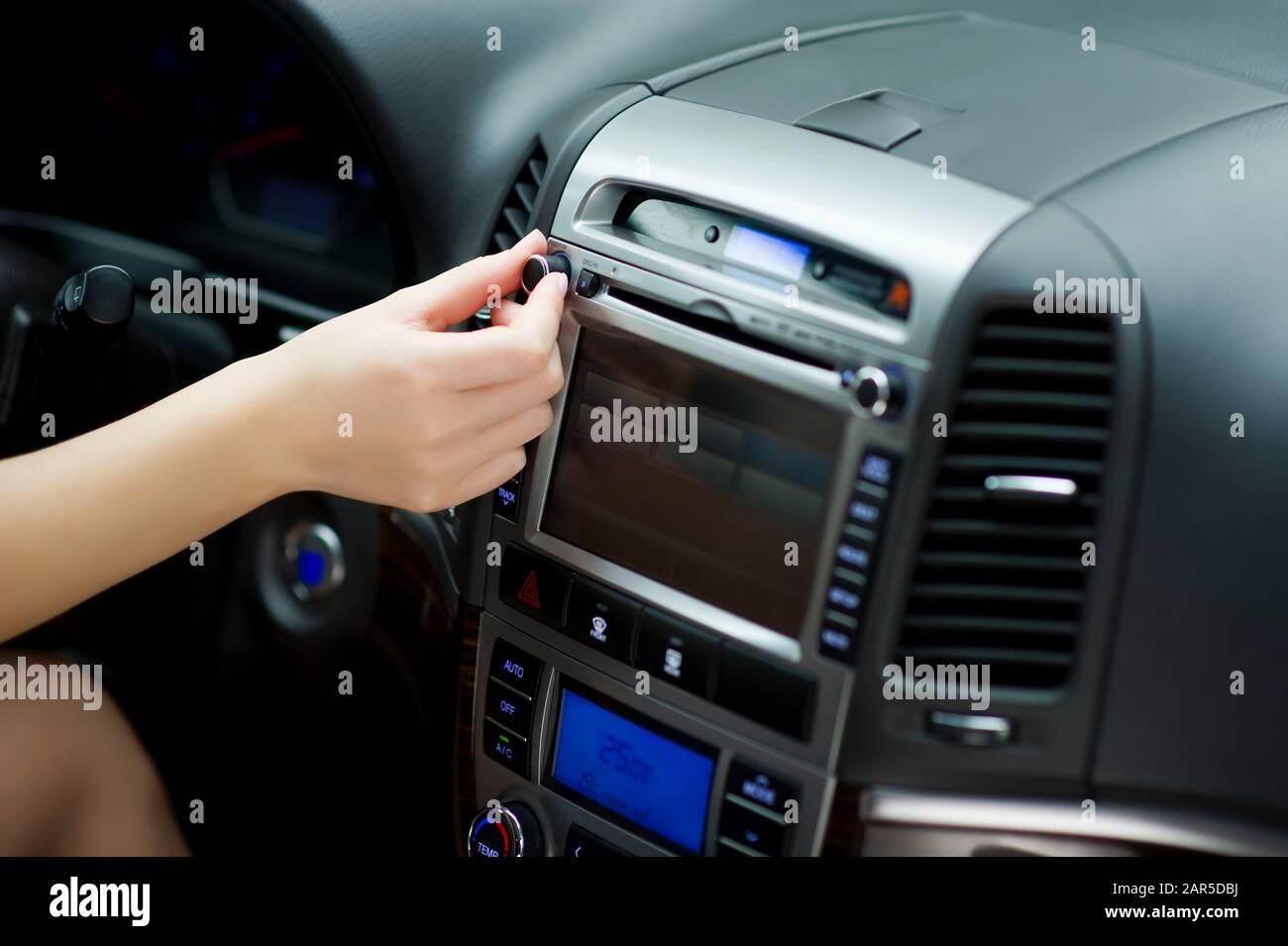 la mano si sintonizza nelle stazioni radio e regola il volume dell'audio sull'impianto audio dell'auto. Foto Stock