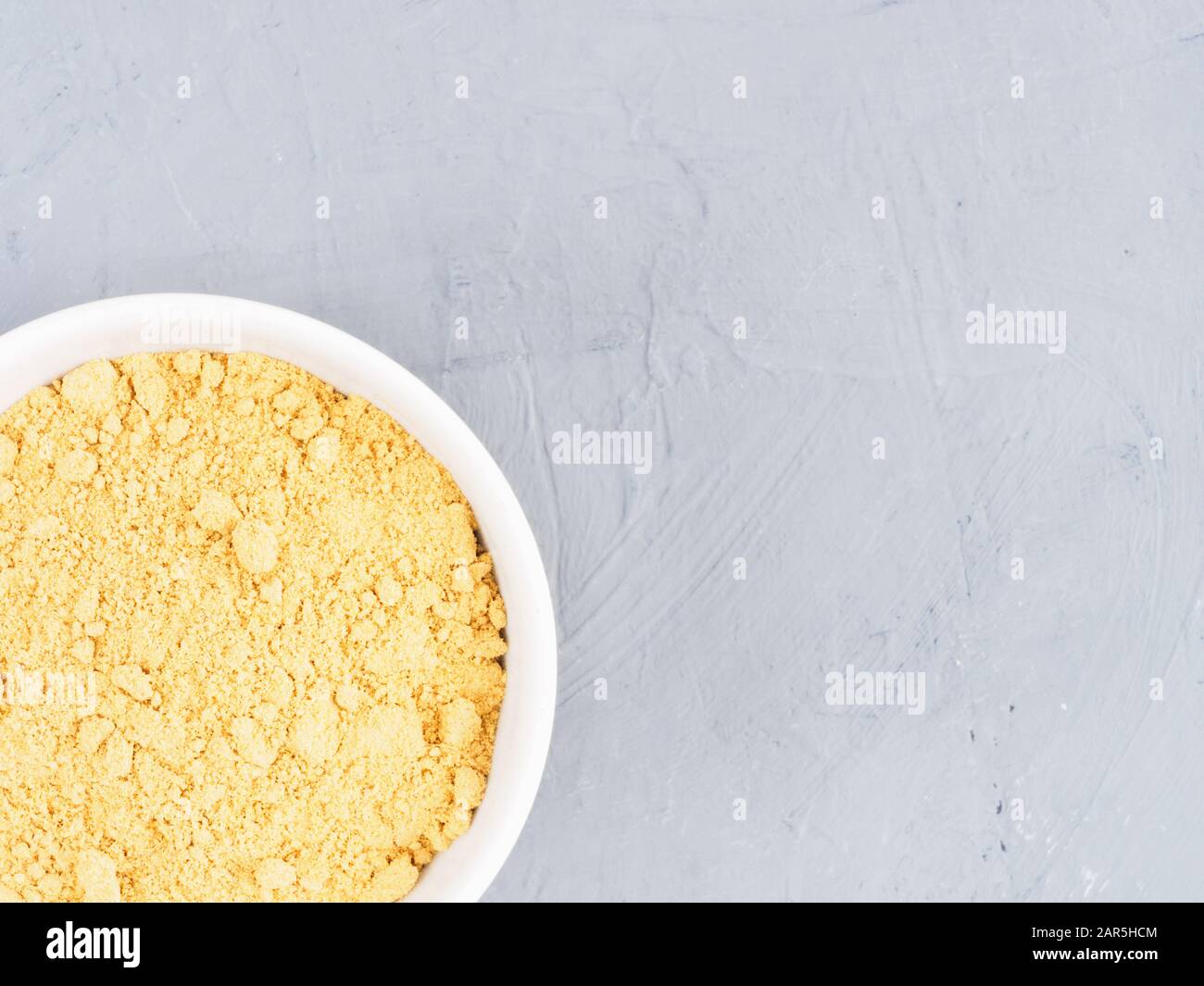 Polvere di zenzero secca in una ciotola bianca su sfondo grigio in cemento con spazio per la copia. Concetto di alimentazione sana Foto Stock