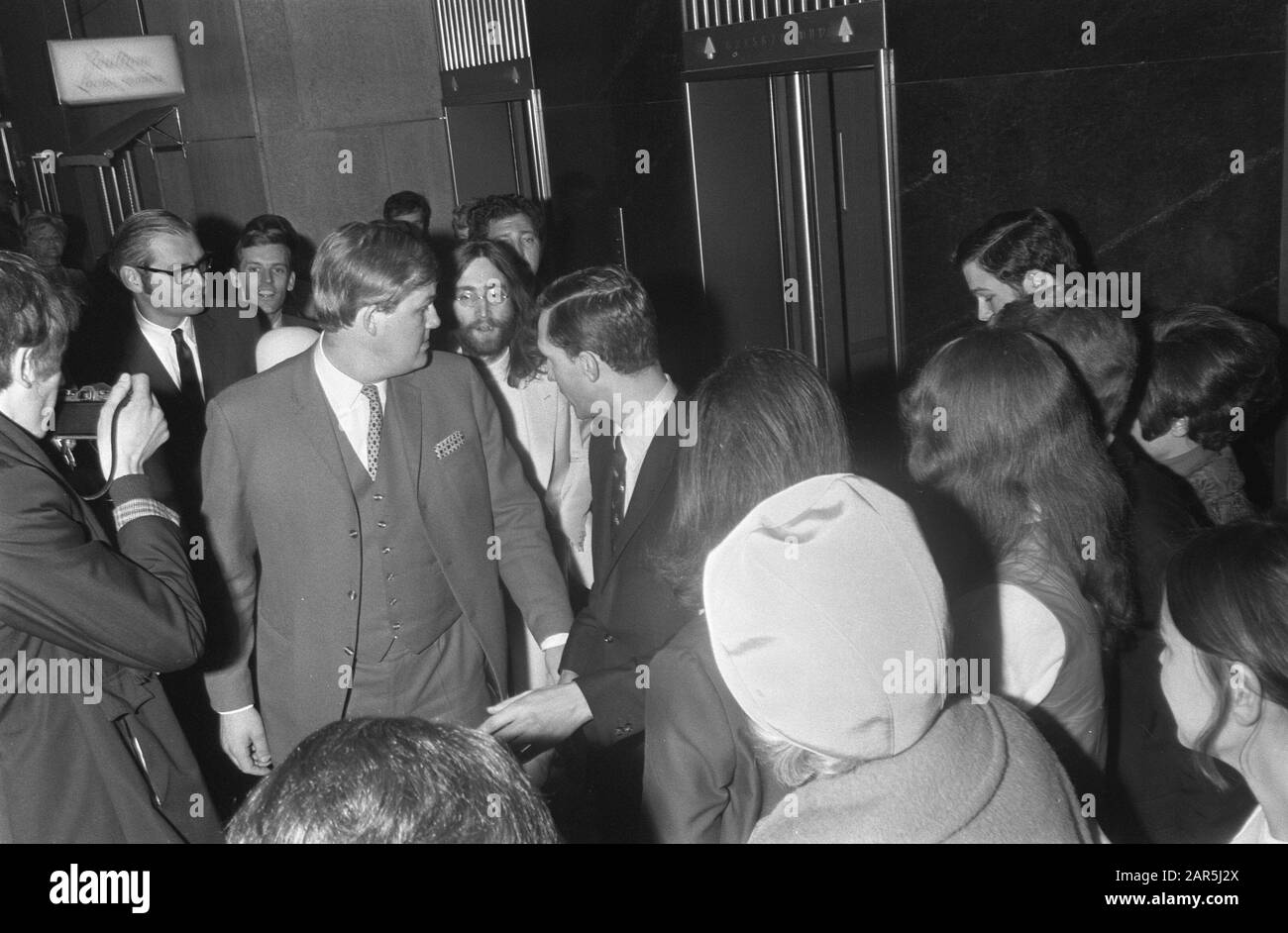 John Lennon e moglie Yoko Ono lasciate l'Hilton Hotel ad Amsterdam, circondato da persone di sicurezza Data: 31 Marzo 1969 posizione: Amsterdam, Noord-Holland Parole Chiave: Arrivo e partenza, coppie, musicisti Nome personale: Lennon, John, Ono, Yoko Foto Stock