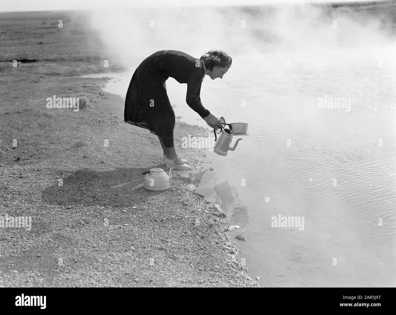 Islanda giovane donna versa acqua calda da una sorgente calda in una brocca Data: 1934 luogo: Islanda Parole Chiave: Paesaggi, donne, paesaggio vulcanico, calore, fonti d'acqua Foto Stock
