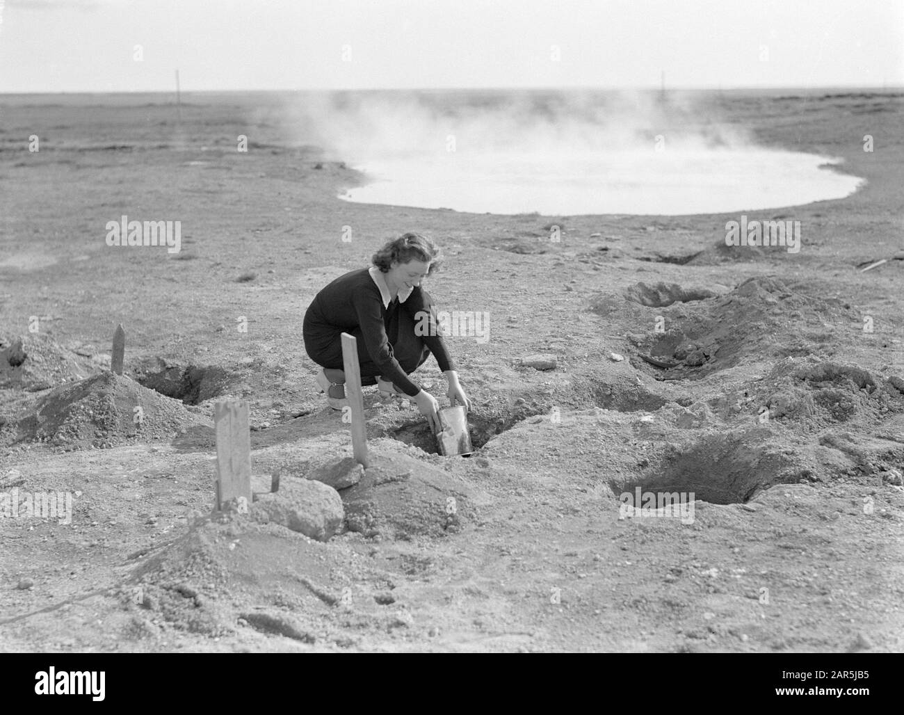 Islanda giovane donna ferma una lattina di pasta nella terra calda per cuocere il pane Data: 1934 posizione: Islanda Parole Chiave: Panettieri, pane, paesaggi, donne, paesaggio vulcanico Foto Stock