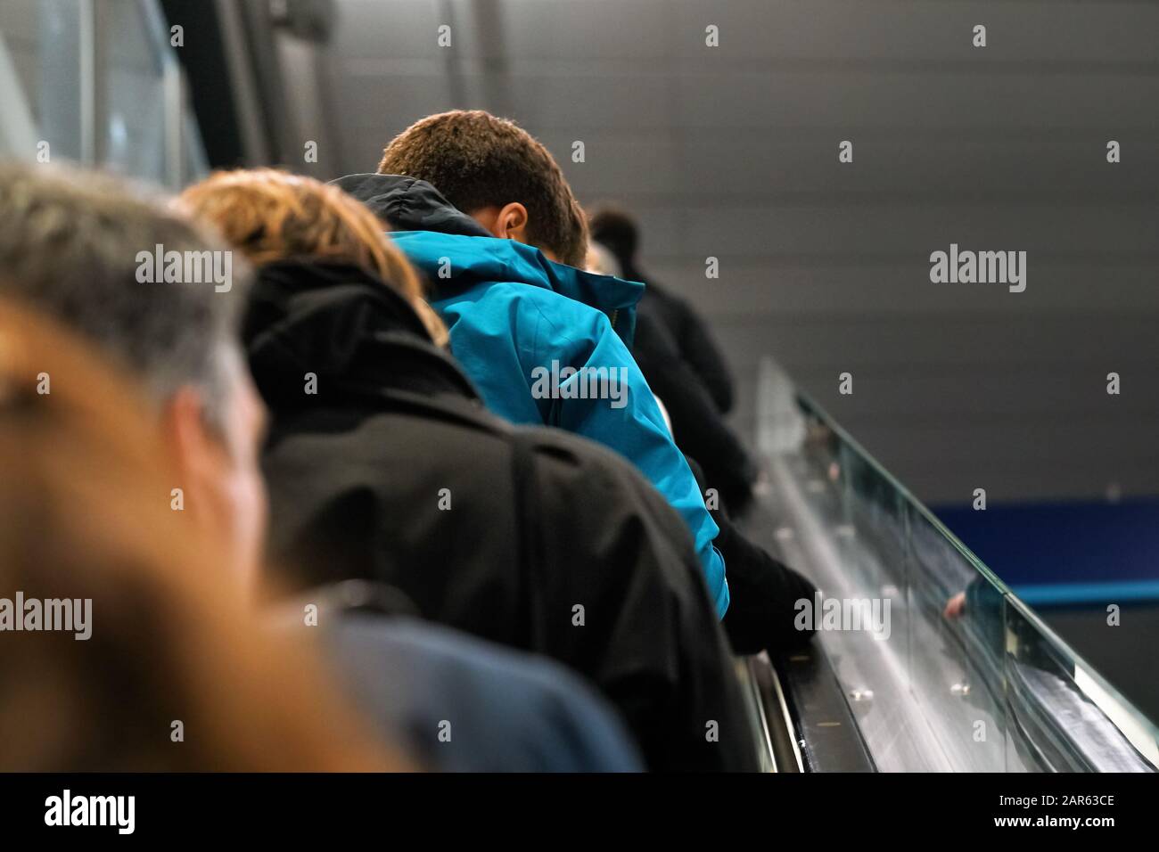 Persone anonime che si muovono su scale mobili, vista da dietro, dettaglio sulla loro testa - concetto di trasporto Foto Stock