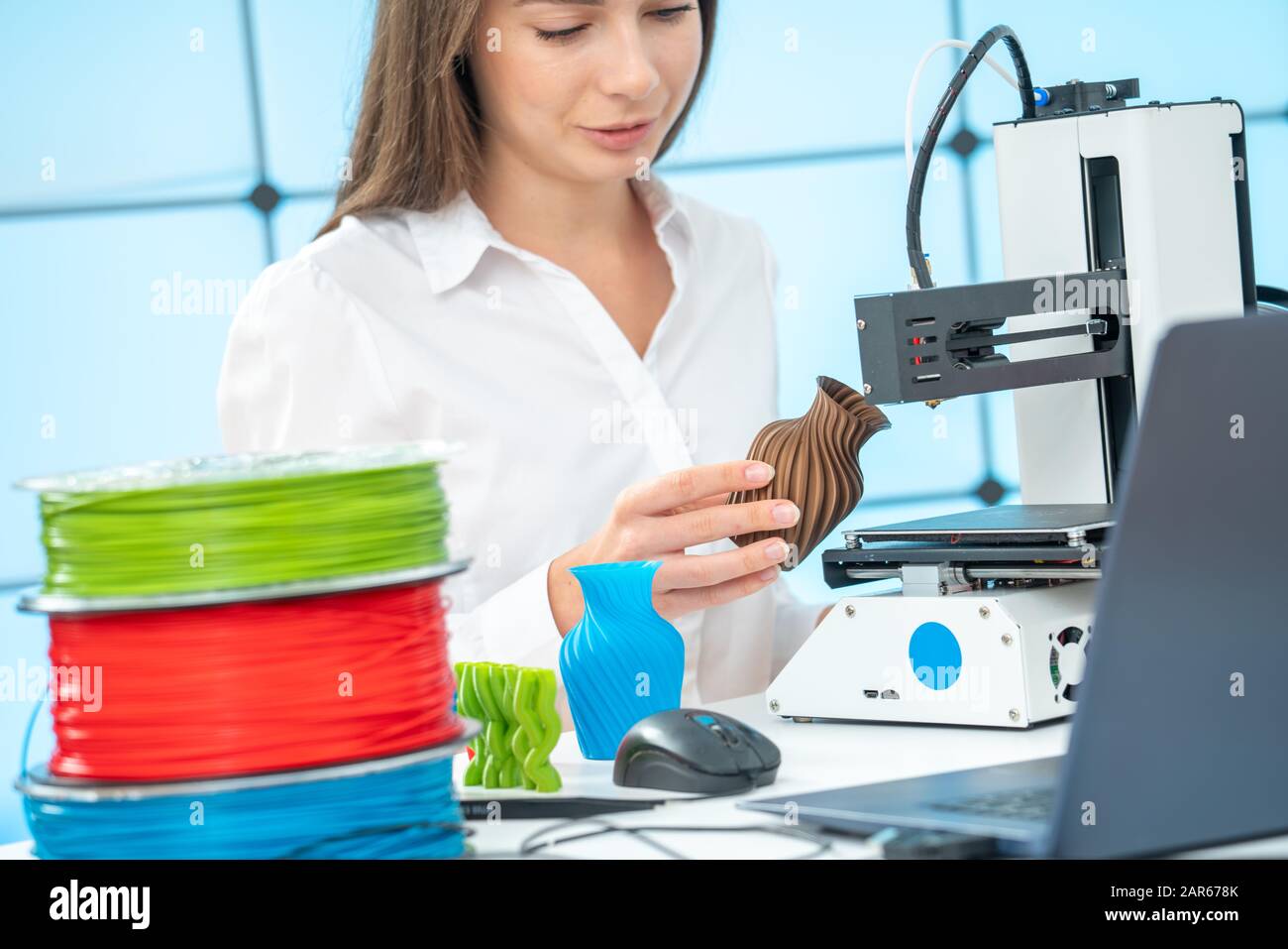 Giovane designer femminile lavora con una stampante 3D in uno studio di design Foto Stock