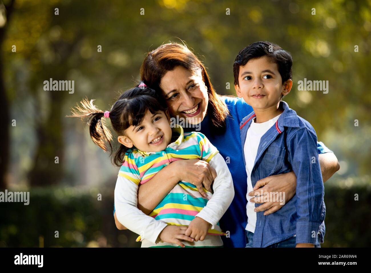 Amare la nonna abbracciando i nipoti al parco all'aperto Foto Stock