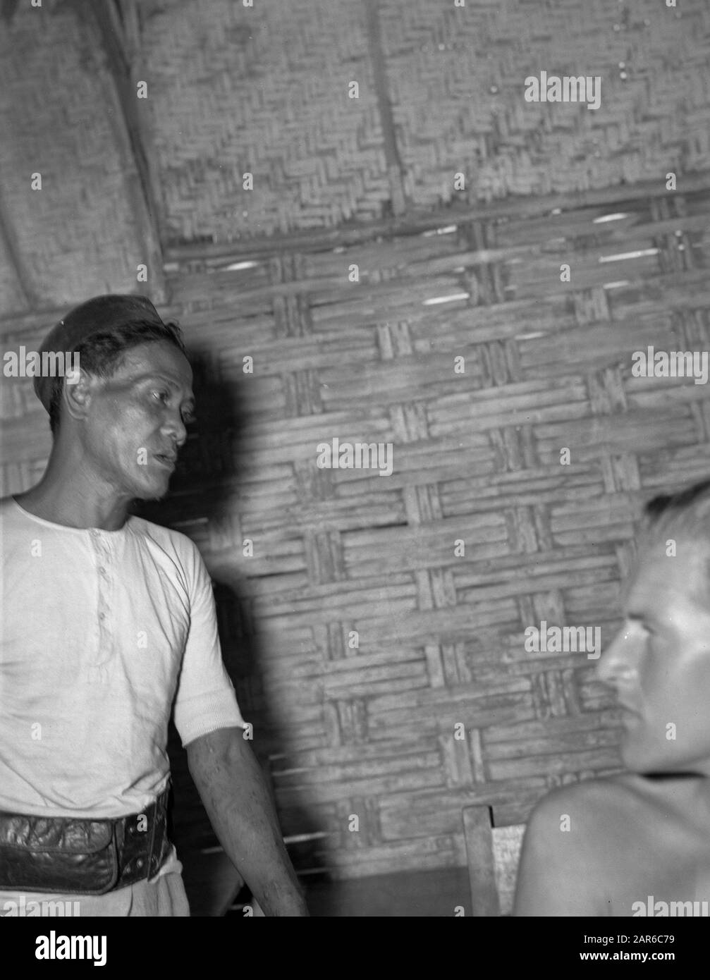 Nikola Drakulic (fotografo) popolazione locale. Un uomo indonesiano con in primo piano il volto di un militare Nedelrandse Data: 1946/01/01 luogo: Indonesia, Indie orientali olandesi Foto Stock