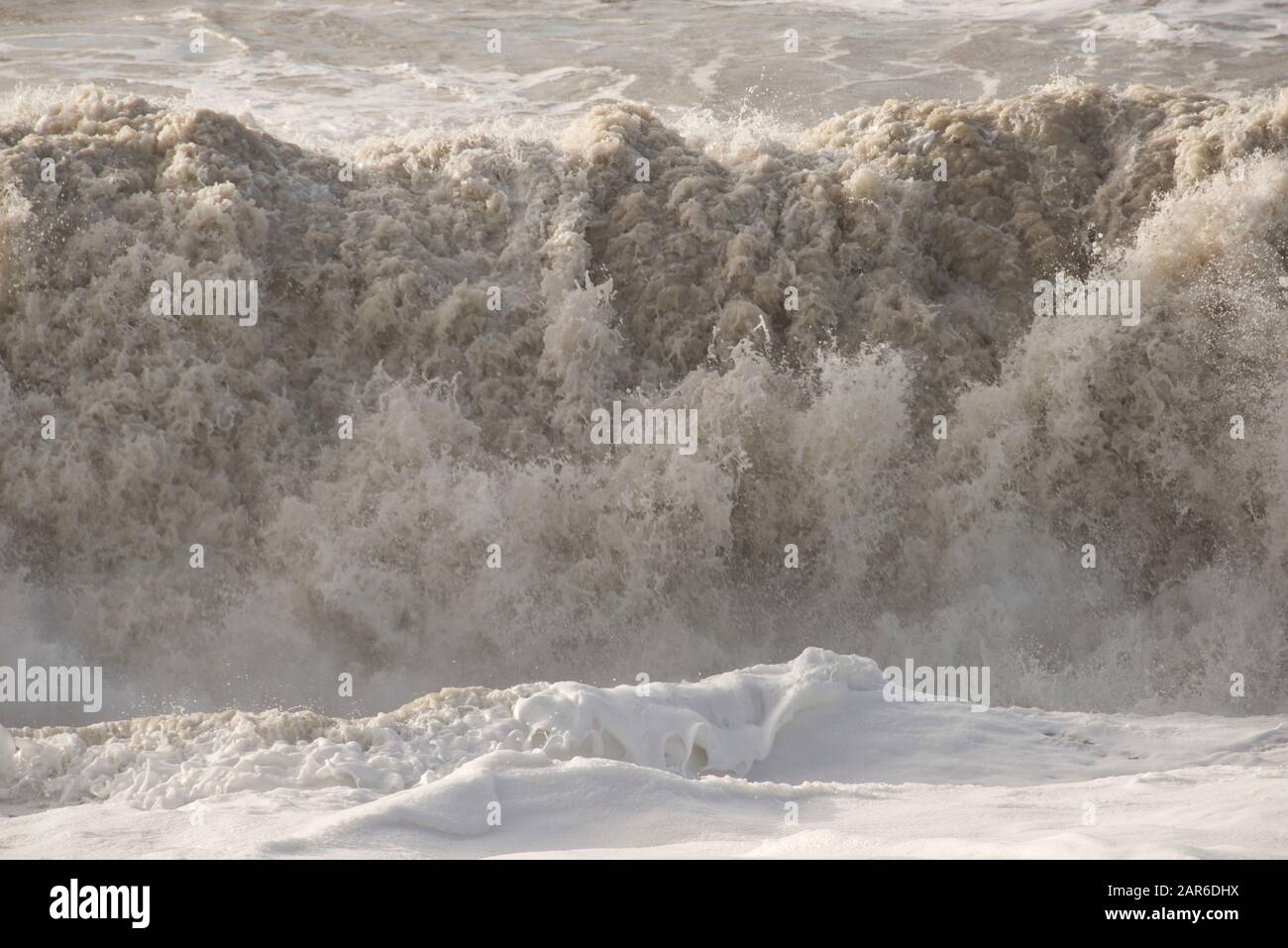 Onde alte, infrangono da una tempesta della Manica con sabbia da spiaggia montata che erode la costa su Hive Beach, Dorset, gennaio Foto Stock