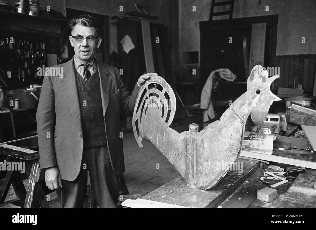 Haantje è soffiato dalla torre della chiesa a Steenwijk Man posa in opere comunali accanto al gallo soffiato Data: 2 novembre 1965 Località: Overijssel, Steenwijk Parole Chiave: Chiese Foto Stock