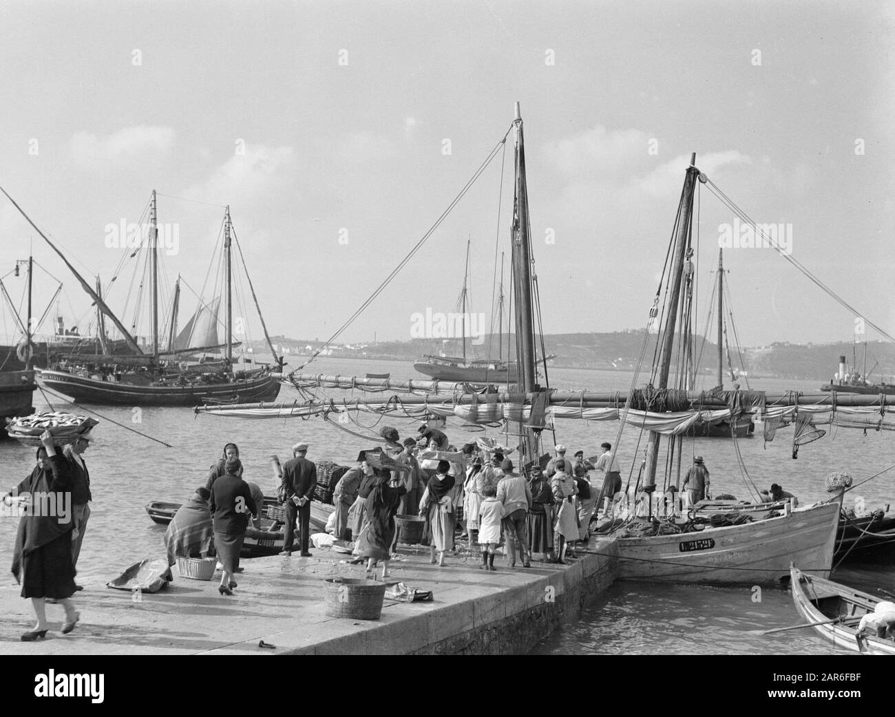 Viaggio in mare con La gente di MS Beroeran su un molo nel porto di pesca di Lisbona; i pescatori caricano la loro cattura da annotazione: Questa foto fa parte di una serie di foto di un viaggio con la MS Beroeran del Lloyd di Rotterdam Data: Maggio 1935 posizione: Lisbona, Portogallo Parole Chiave: Pescherecci Foto Stock