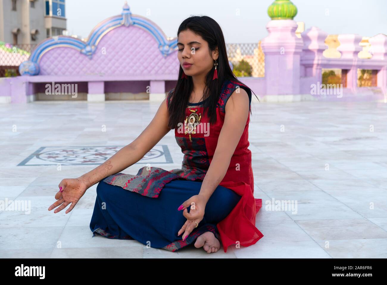 Giovane donna indiana meditando al tempio indù vestito con abiti tradizionali colorati a Vrindavan, Uttar Pradesh, India. Foto Stock