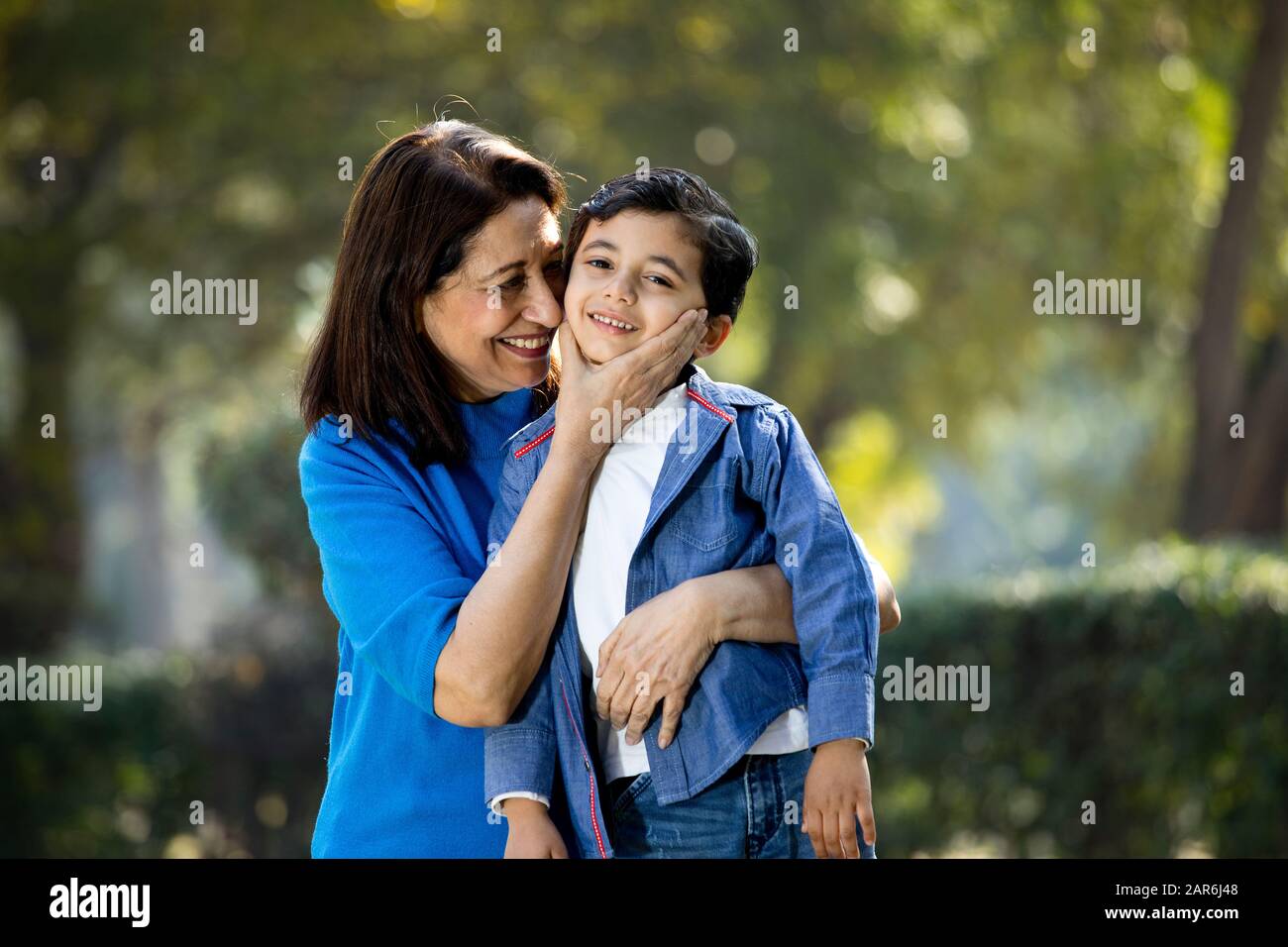 Donna che abbraccia il nipote al parco Foto Stock