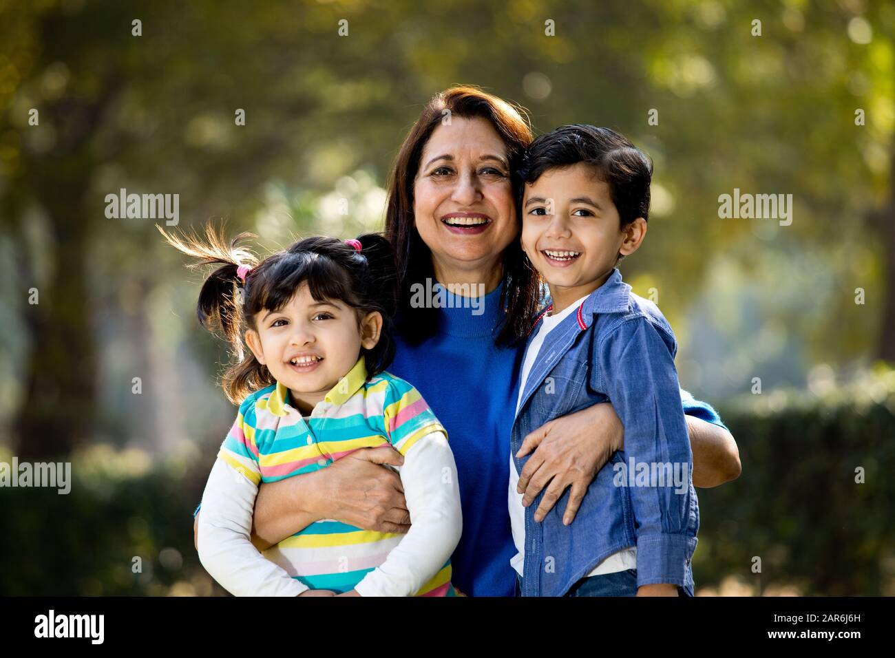 Amare la nonna abbracciando i nipoti al parco all'aperto Foto Stock