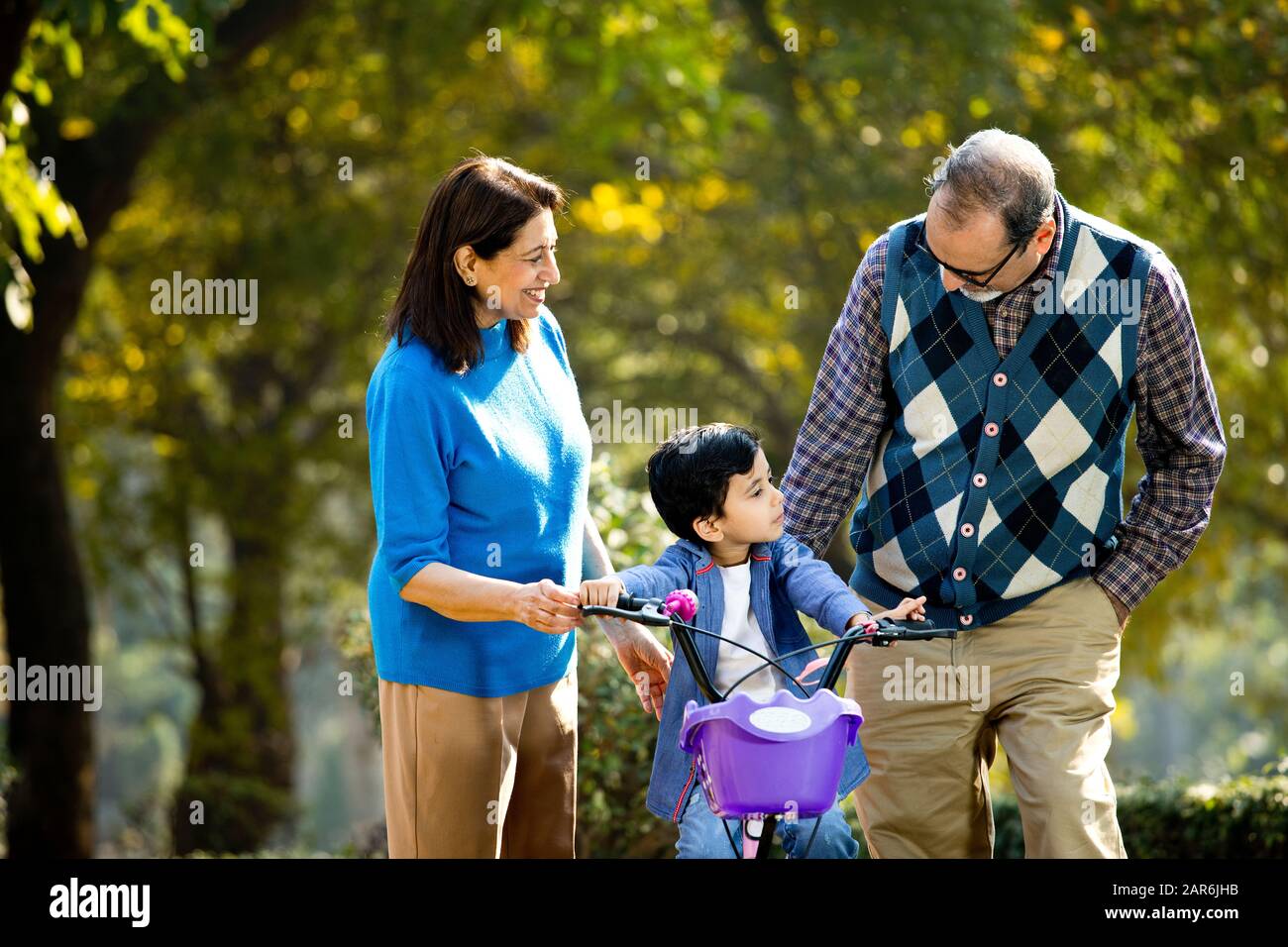 Nonni con nipote imparare a guidare la bicicletta Foto Stock