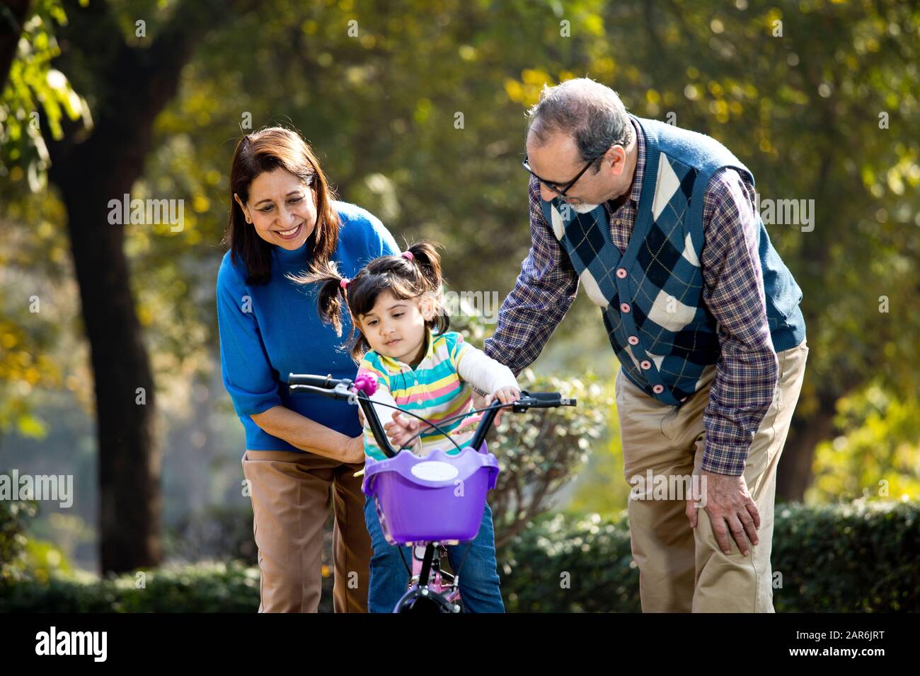 Nonni con nipote imparare a guidare la bicicletta Foto Stock