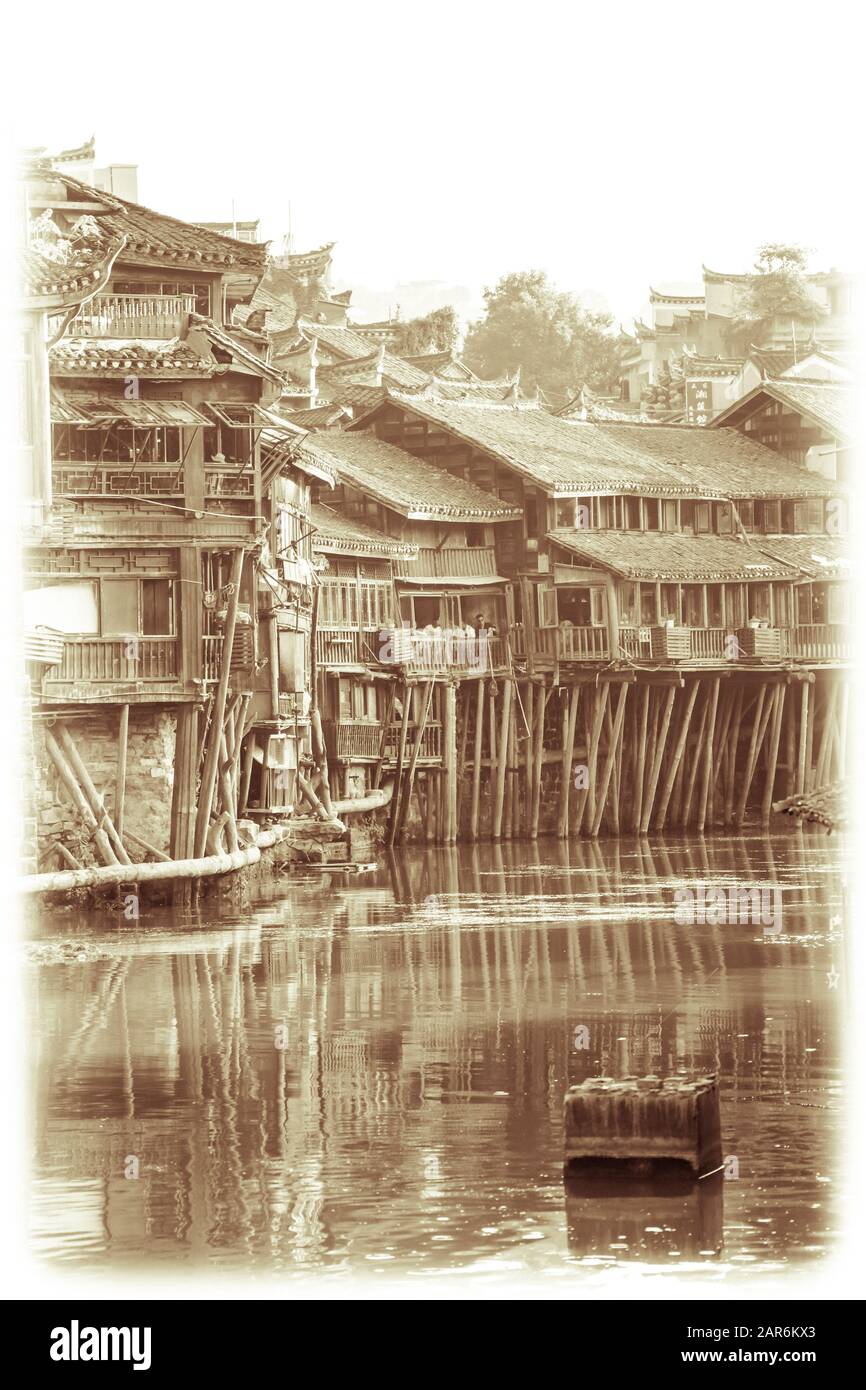 Feng Huang, Cina - Agosto 2019 : Retro d'epoca seppia vista del vecchio storico palafitte Diaojiao case in legno sulle rive del fiume Tuo, che scorre t Foto Stock