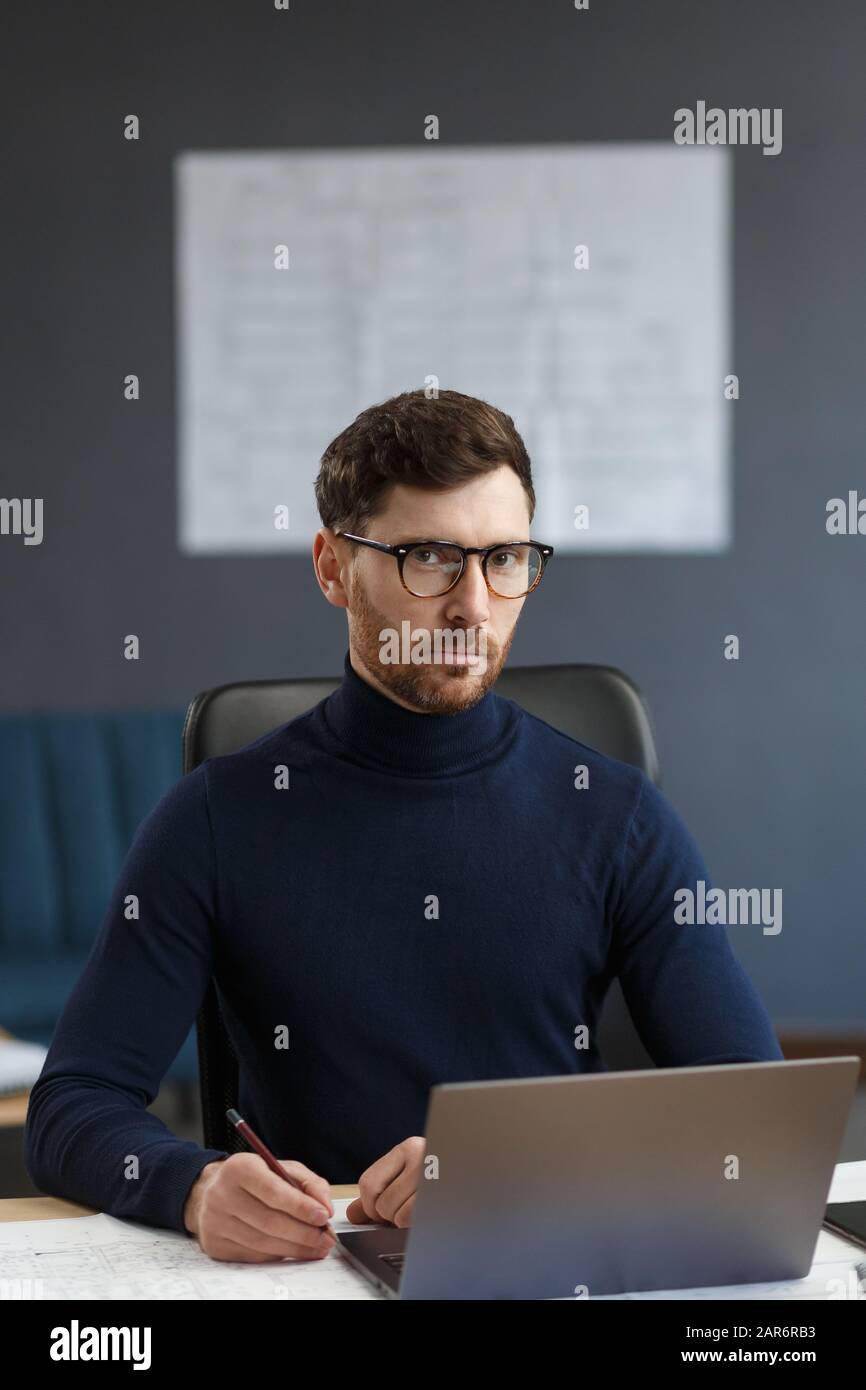 Giovane uomo d'affari che lavora in ufficio con un computer portatile. Ritratto d'affari di bell'uomo portante gli occhiali seduti sul posto di lavoro. Sicuro Foto Stock