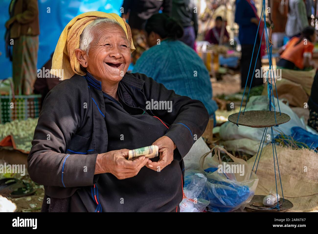 Phaung Daw, Myanmar - 28 dicembre 2019: Donna di Pa'o sorridente anziana al mercato di Phaung Daw Oo con i soldi di una vendita recente Foto Stock