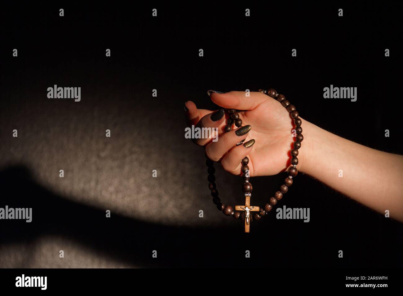 Mano della donna che tiene una croce cristiana. Foto Stock
