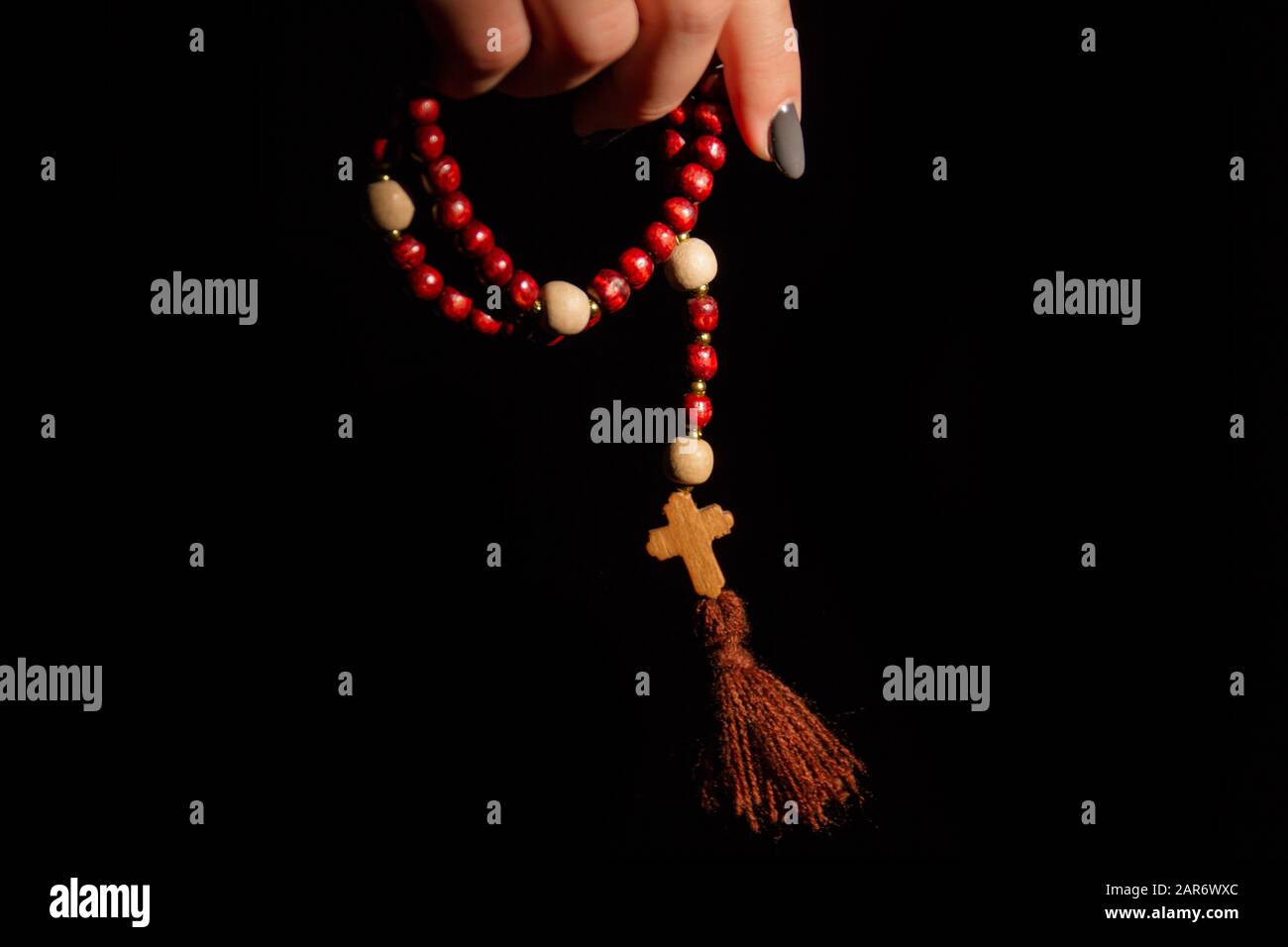 Primo piano di una mano di una donna che tiene perle rosarie. Foto Stock