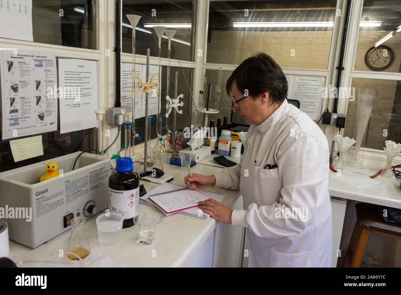 Un tecnico di laboratorio che esamina gli ingredienti della birra presso La famiglia ganci Norton Brewery fondata nel 1849, nel villaggio di Hook Norton villaggio i Foto Stock