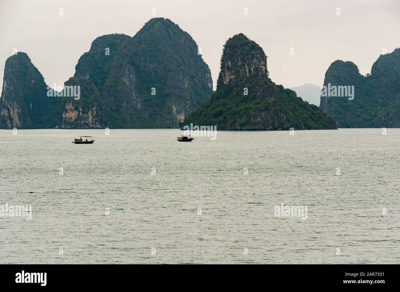 Barche da pesca tradizionali con formazioni rocciose carsiche calcaree, Halong Bay, Vietnam, Asia Foto Stock