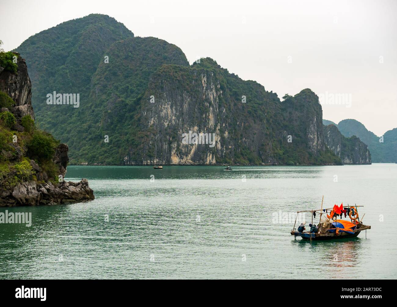 Barca tradizionale vietnamita coracle con formazioni rocciose carsiche calcaree in nebbia meteo, Halong Bay, Vietnam, Asia Foto Stock
