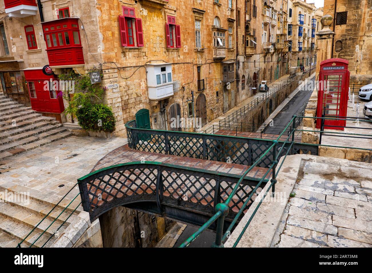 Vecchia città di il-Belt Valletta a Malta, case tradizionali, ponte pedonale su via Liesse, il Bridge Bar e cabina telefonica rossa Foto Stock