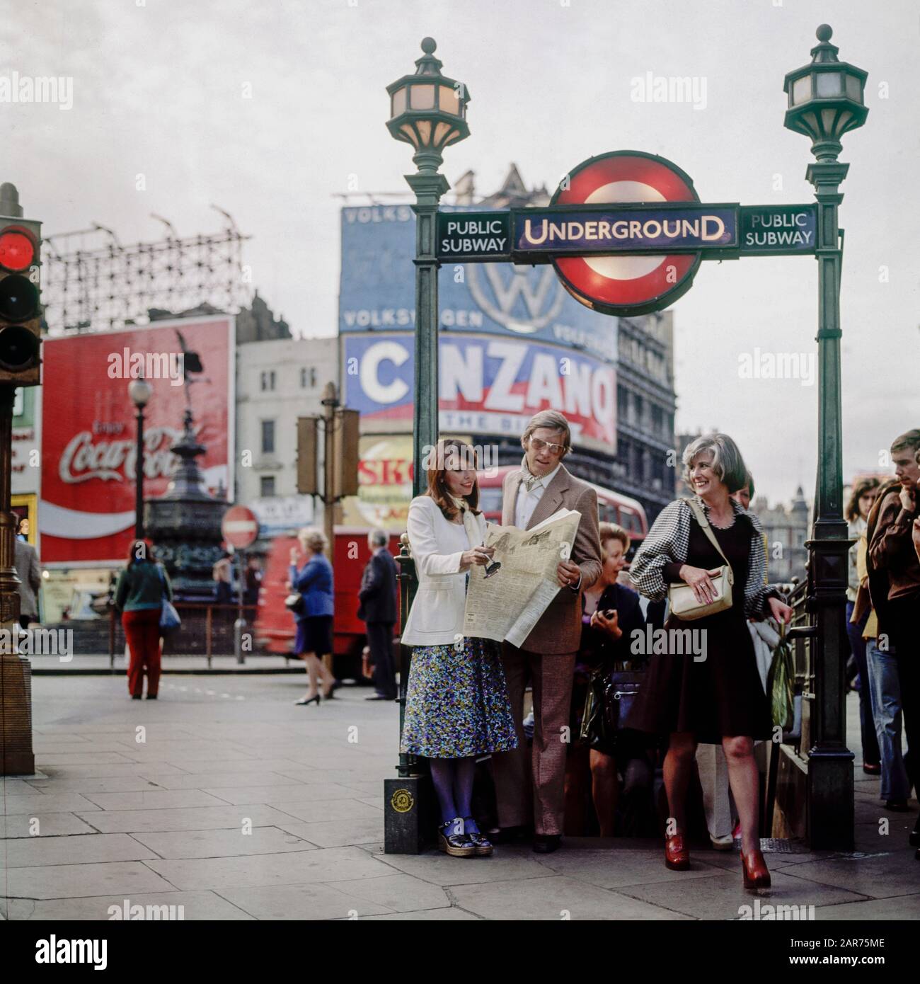 London 1970s, elegante giornale di lettura della coppia, uscita metropolitana pubblica, metropolitana segno, sera, Piccadilly Circus, Inghilterra, Regno Unito, GB, Gran Bretagna, Foto Stock