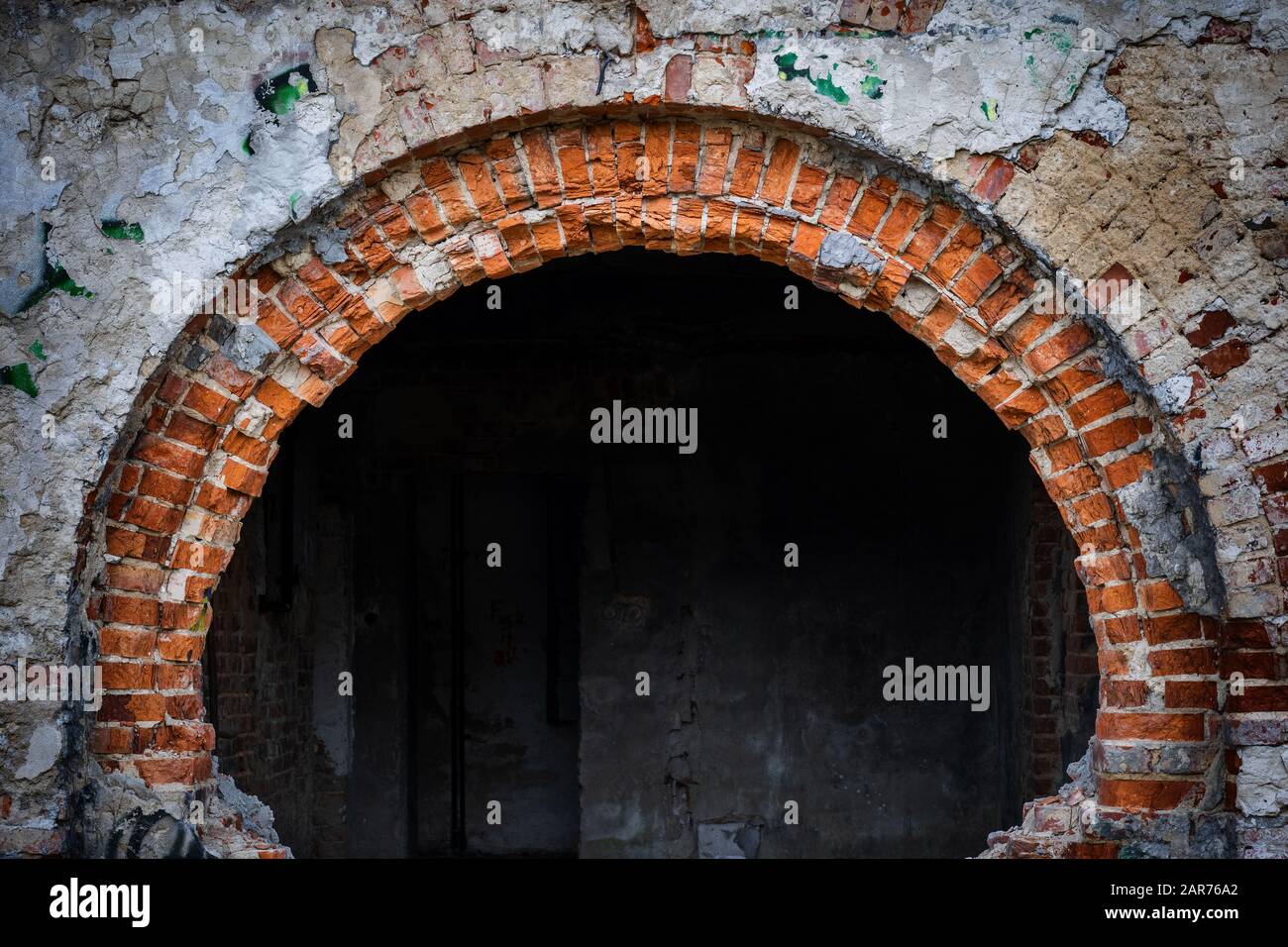 Grande arco in mattoni di un palazzo abbandonato tipo edificio residenziale e camera scura all'interno Foto Stock