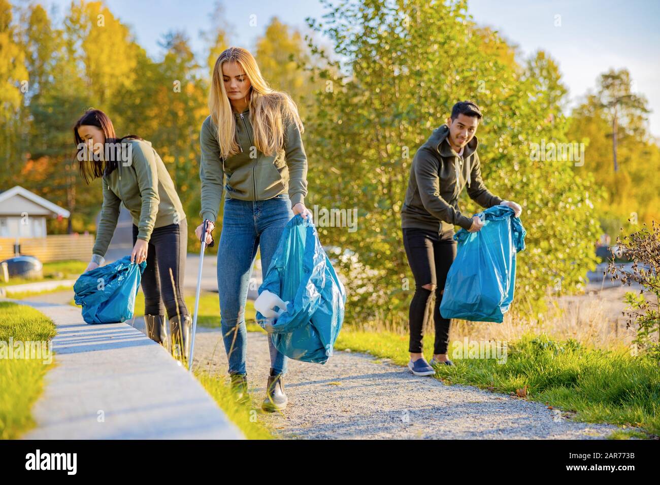 Giovani volontari raccogliere rifiuti in borsa al parco Foto Stock