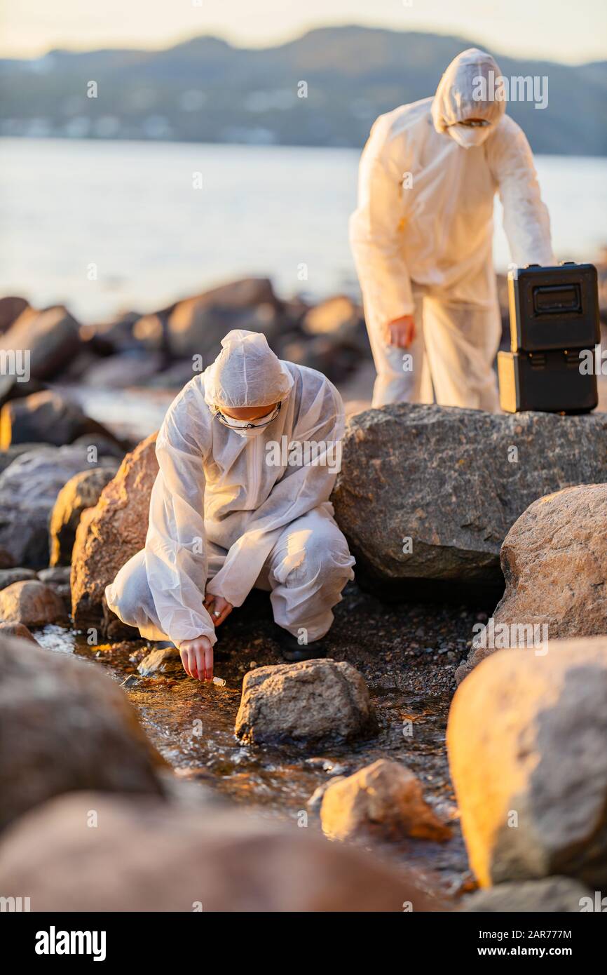 Scienziato che raccoglie il campione d'acqua in riva al mare Foto Stock