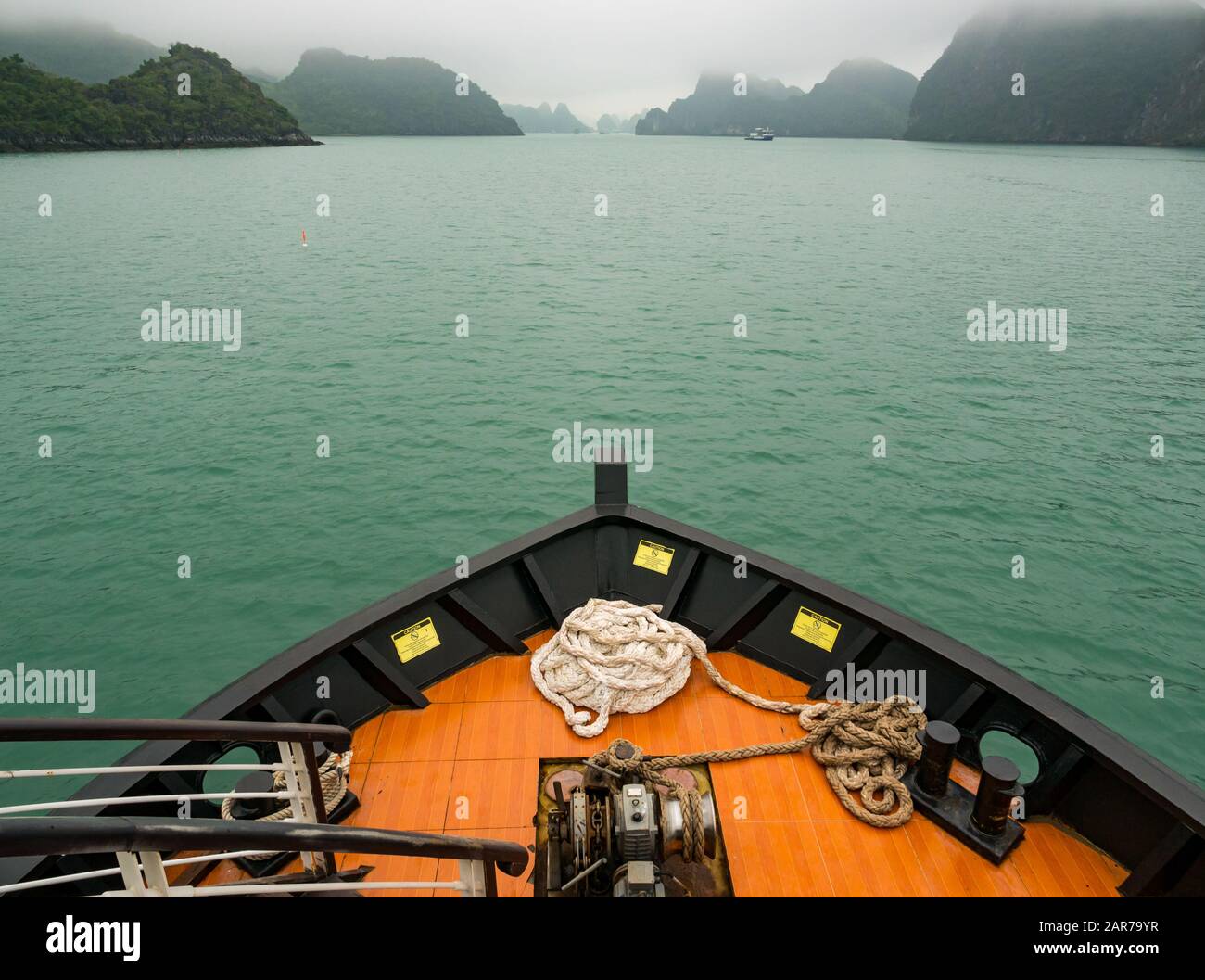 Prua della nave da crociera che si dirige verso formazioni rocciose carsiche calcaree in nebbia, Halong Bay, Vietnam, Asia Foto Stock