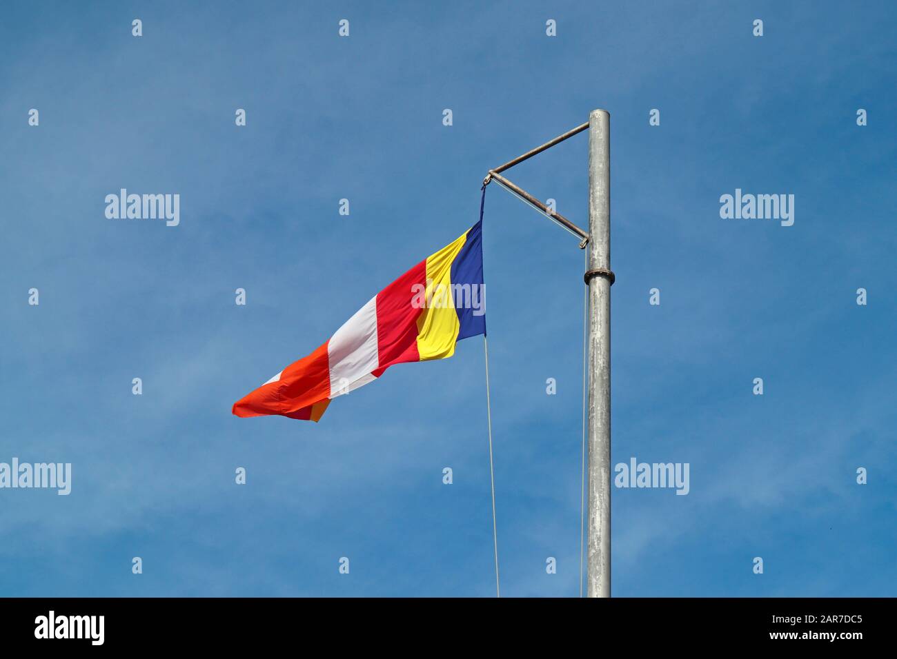 La bandiera buddista su un palo di bandiera di acciaio galvanizzato contro un cielo blu Foto Stock