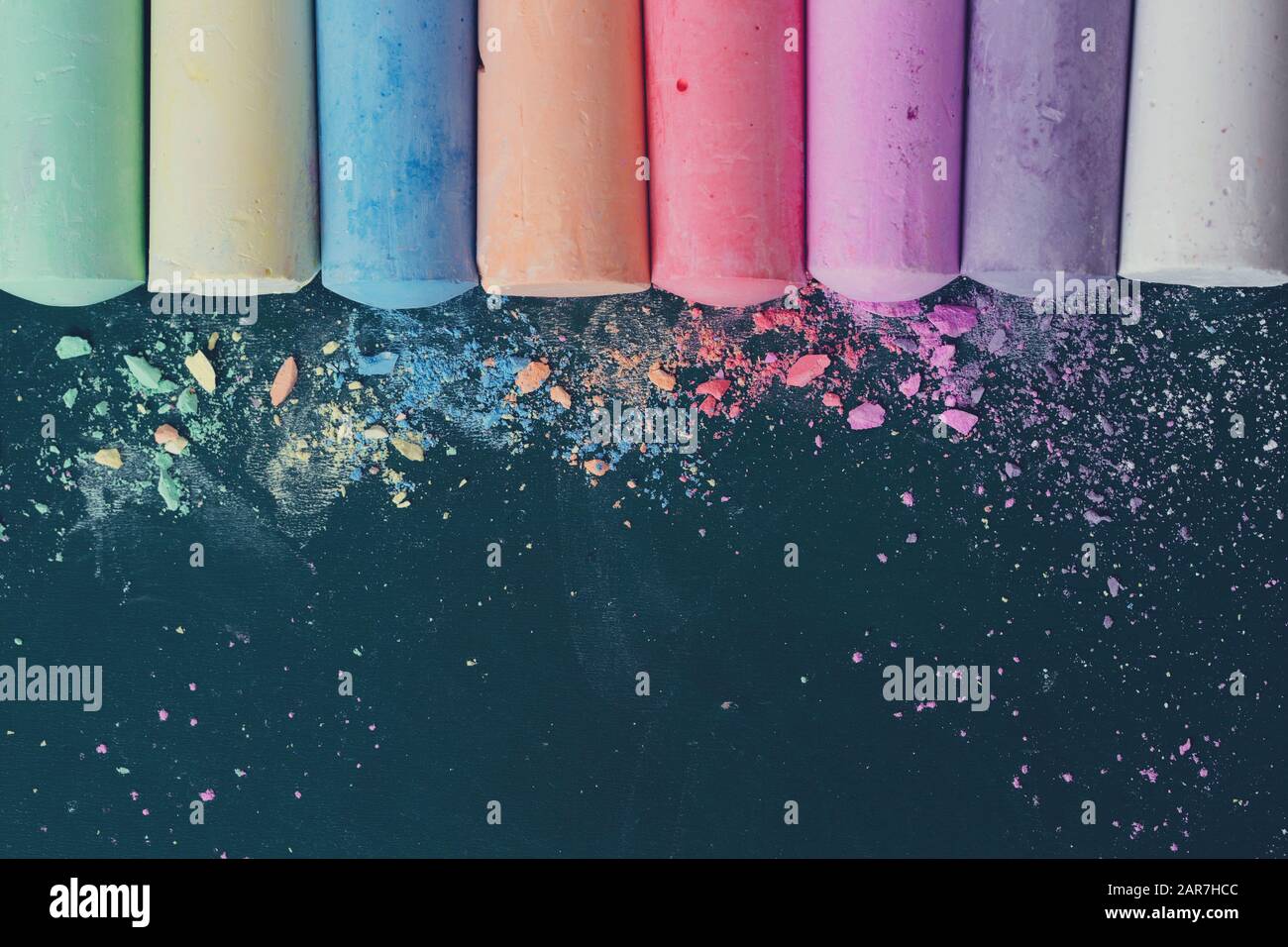 Briciole e pezzetti di gesso multicolore, pastelli sul tabellone della scuola. Giallo, rosa, rosso, verde, grigio, verde chiaro Foto Stock