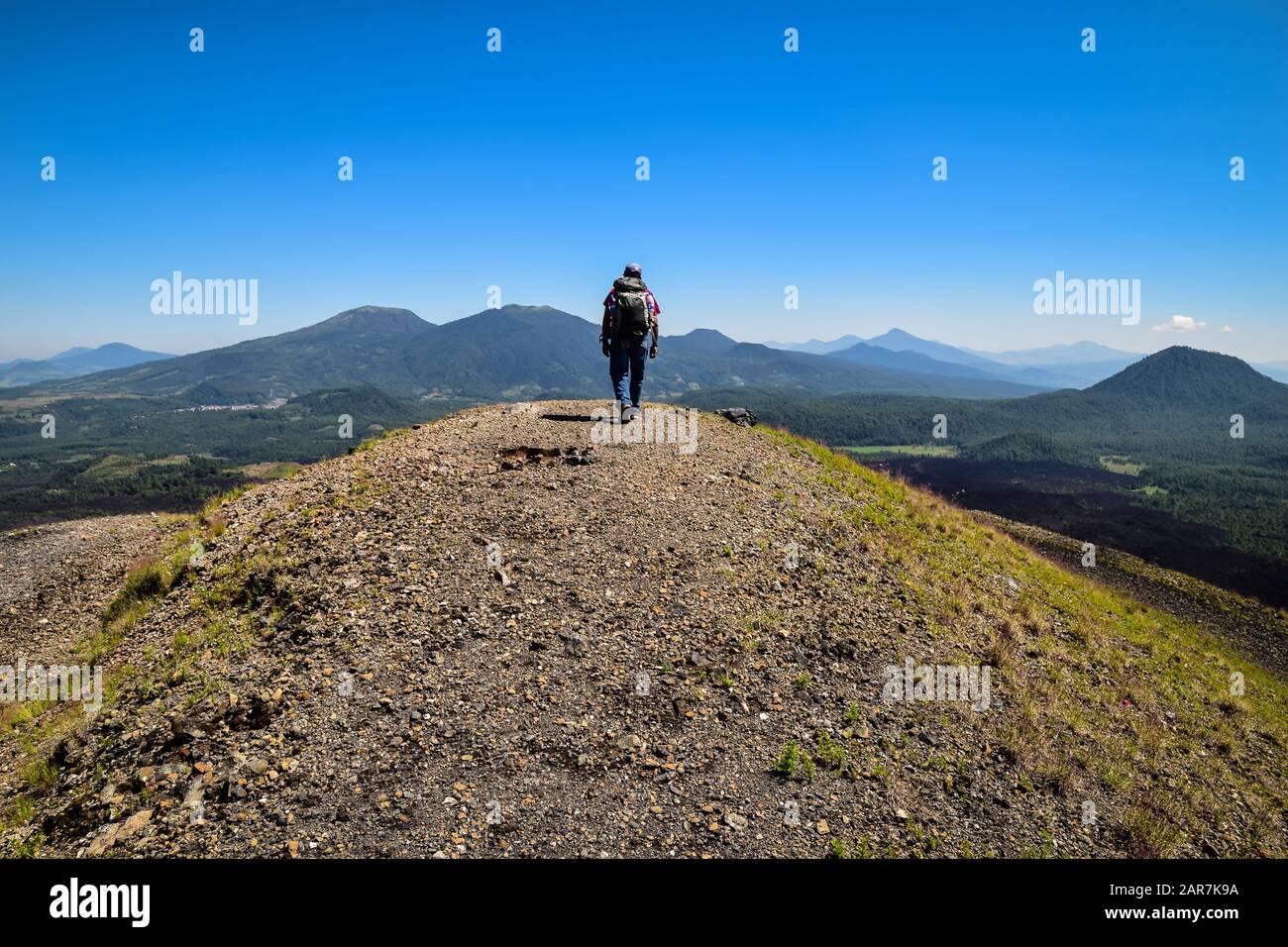 Uomo che cammina fino alla cima di un crinale di una caldera vulcanica in un paesaggio montuoso, Paricutin, Messico Foto Stock